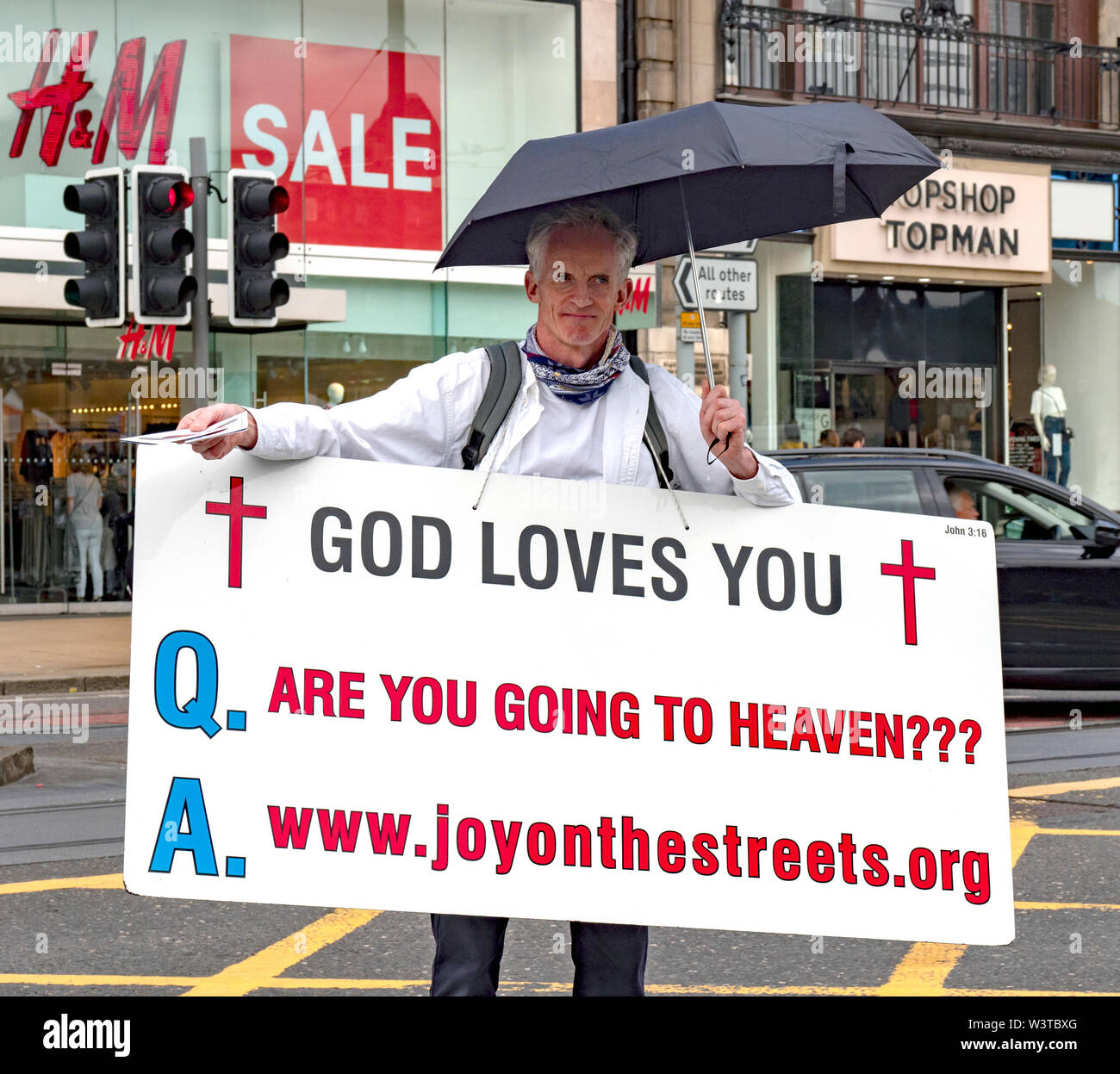 A man holding a placard that reads 'God Loves You' and Are you Going to Heaven' Stock Photo