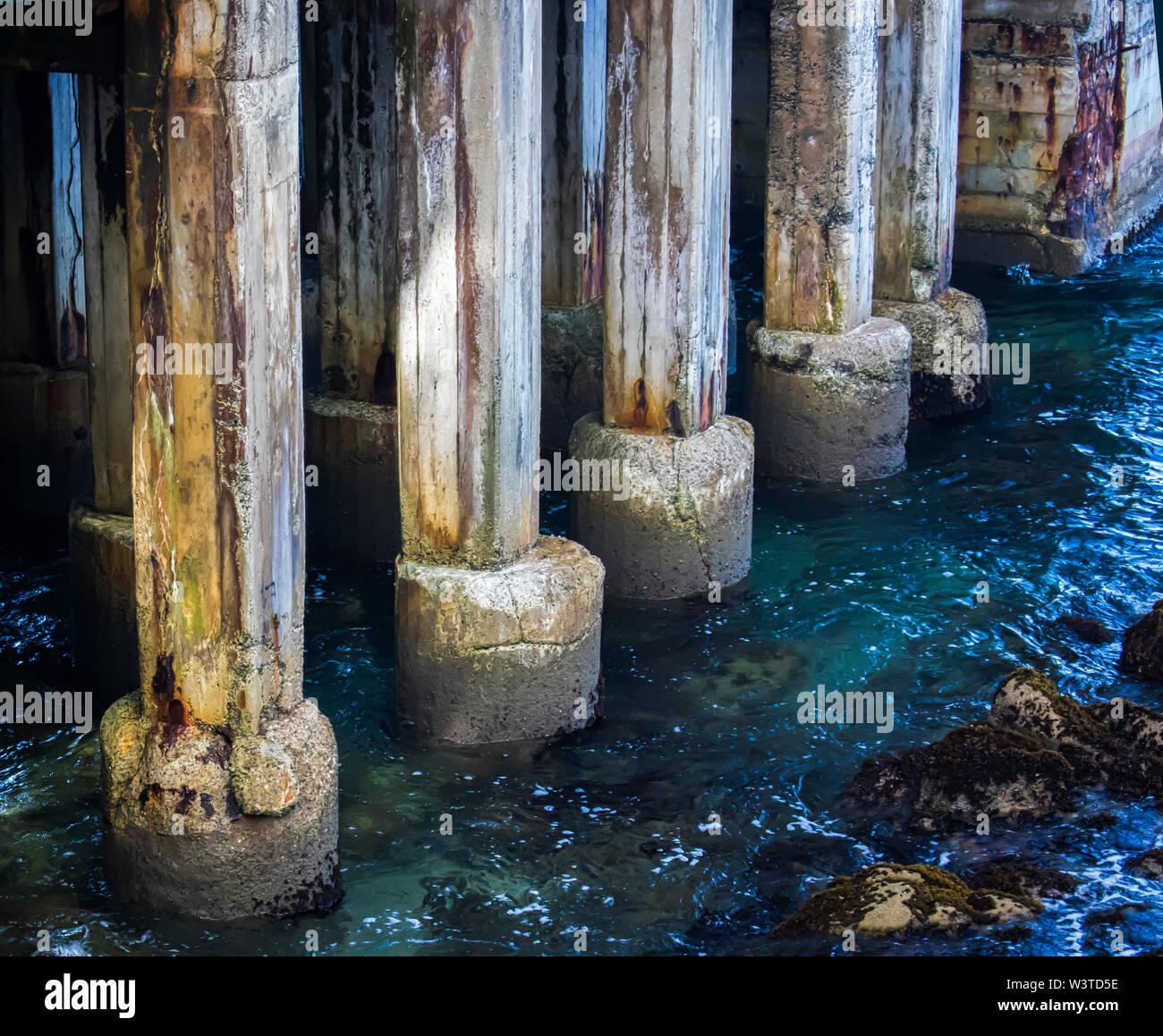 Aging pier pilings close up with blue clear ocean water in Monterey, California. Stock Photo
