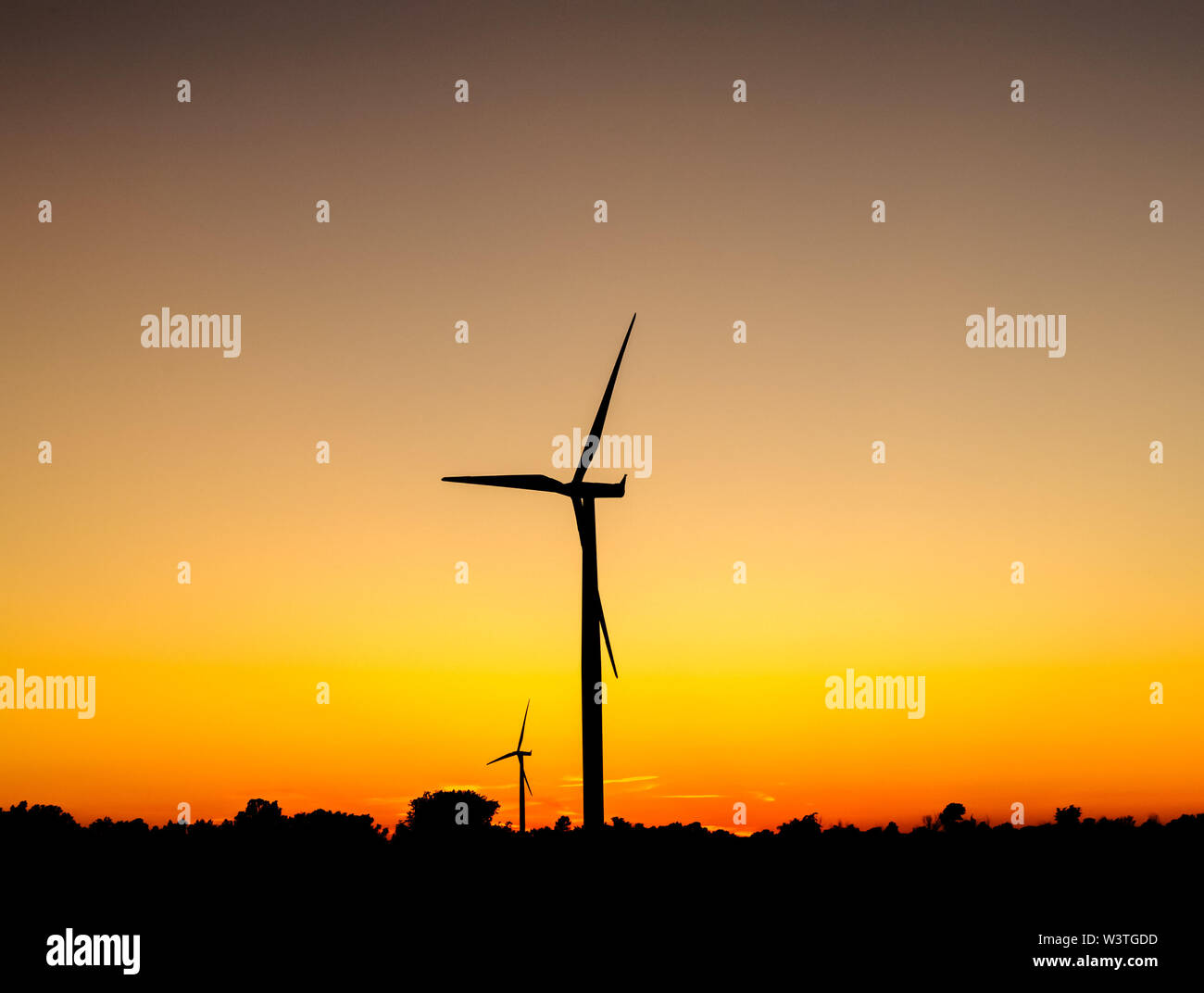 Black silhouette of wind turbines against orange sky at dusk Stock ...