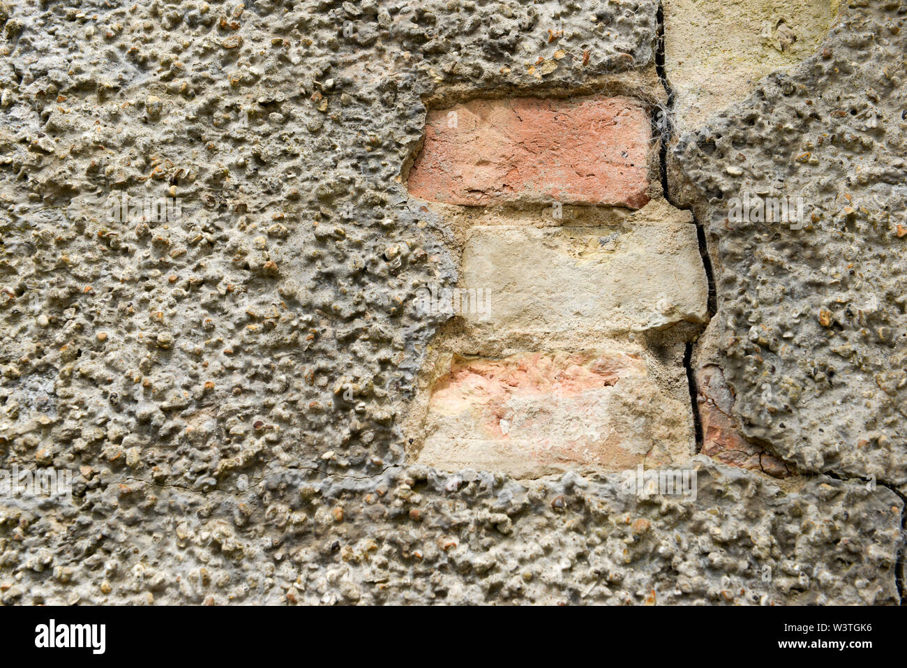Bricks showing where weather has eroded away at the rendering causing