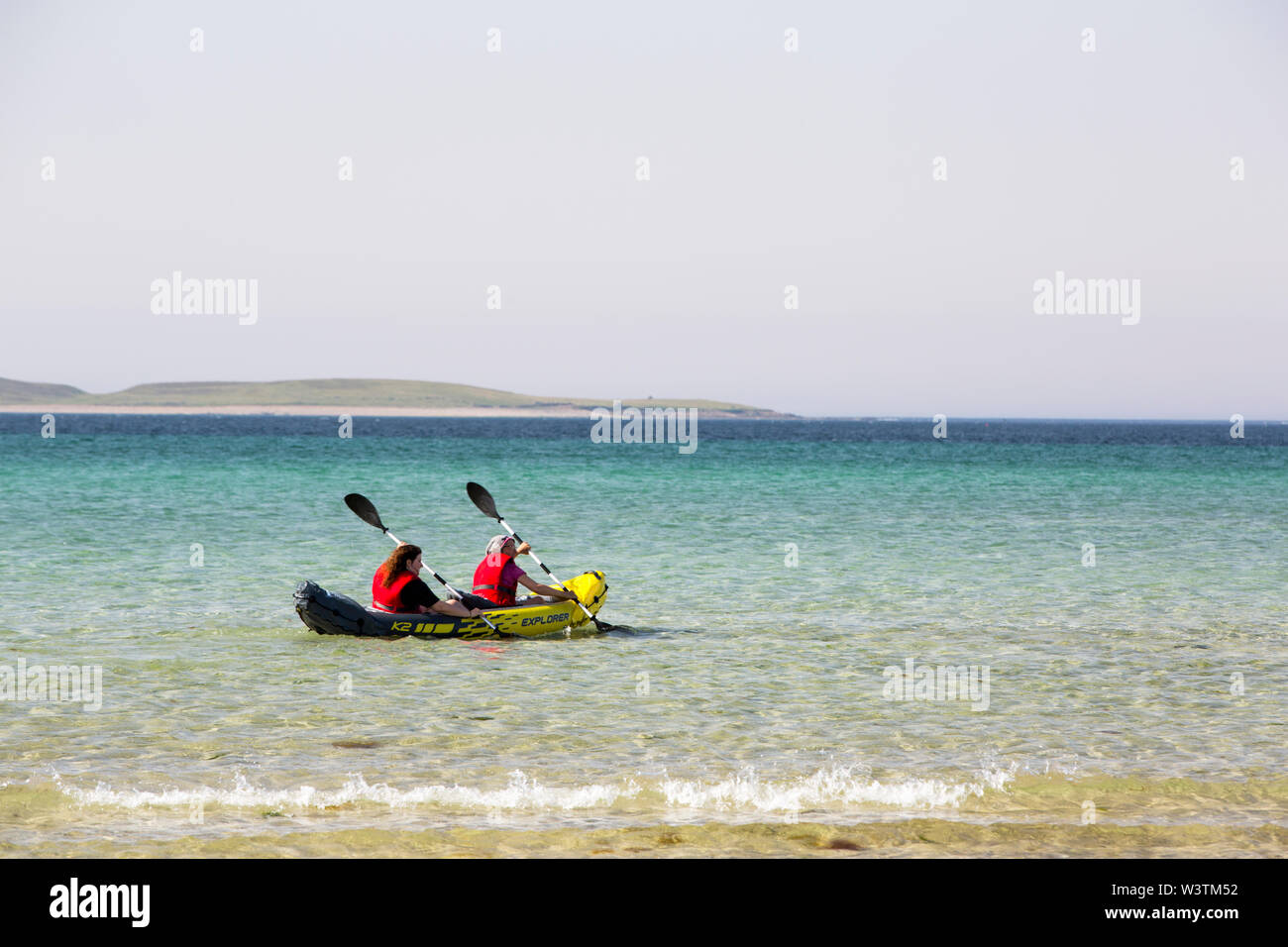 Woman paddling an inflateable sea kayak at Sands of Evie in Eynhallow sound between Orkney, and Rousay, Scotland, UK. Stock Photo