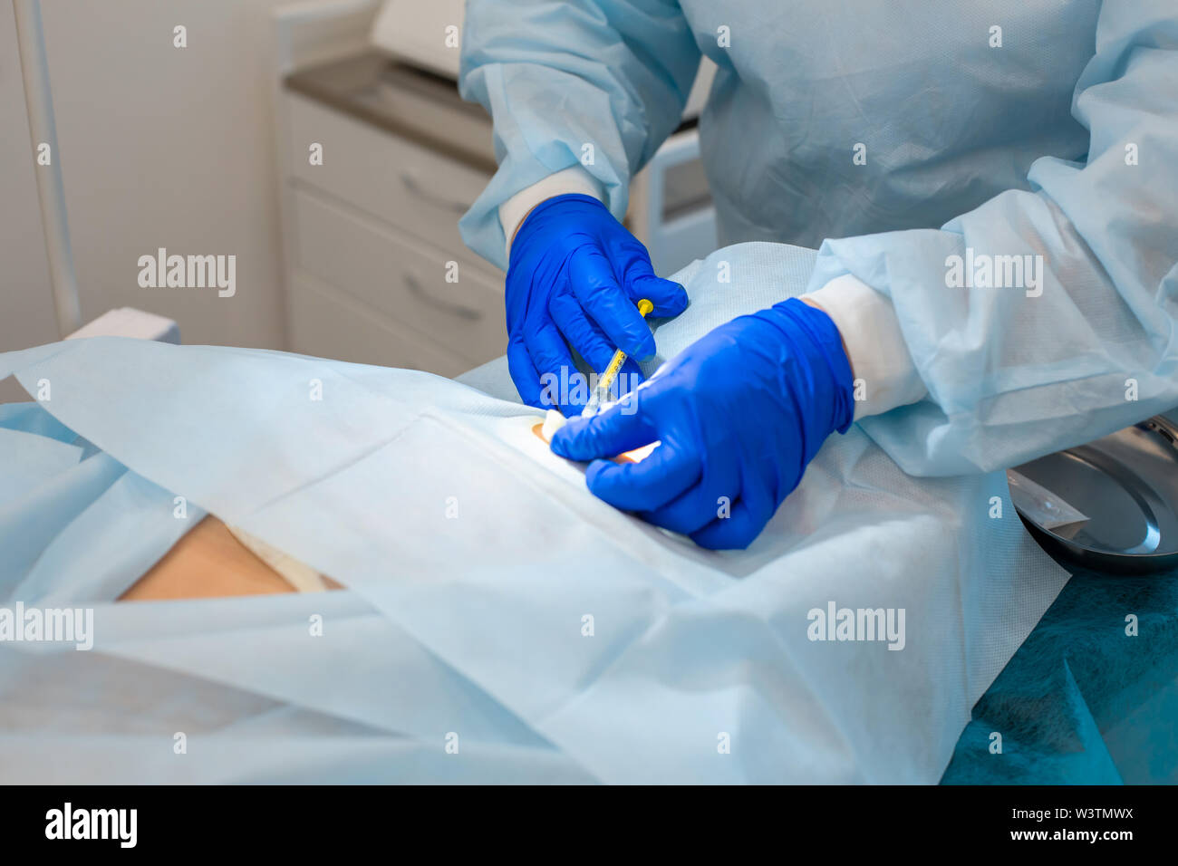 A nurse makes an injection for local anesthesia at the surgical site