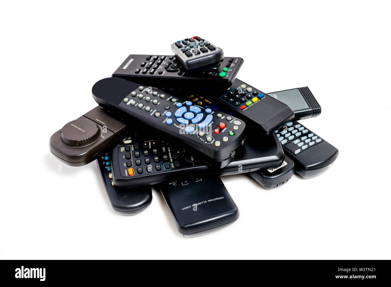 Horizontal shot of a lot of old remote controls piled high. White