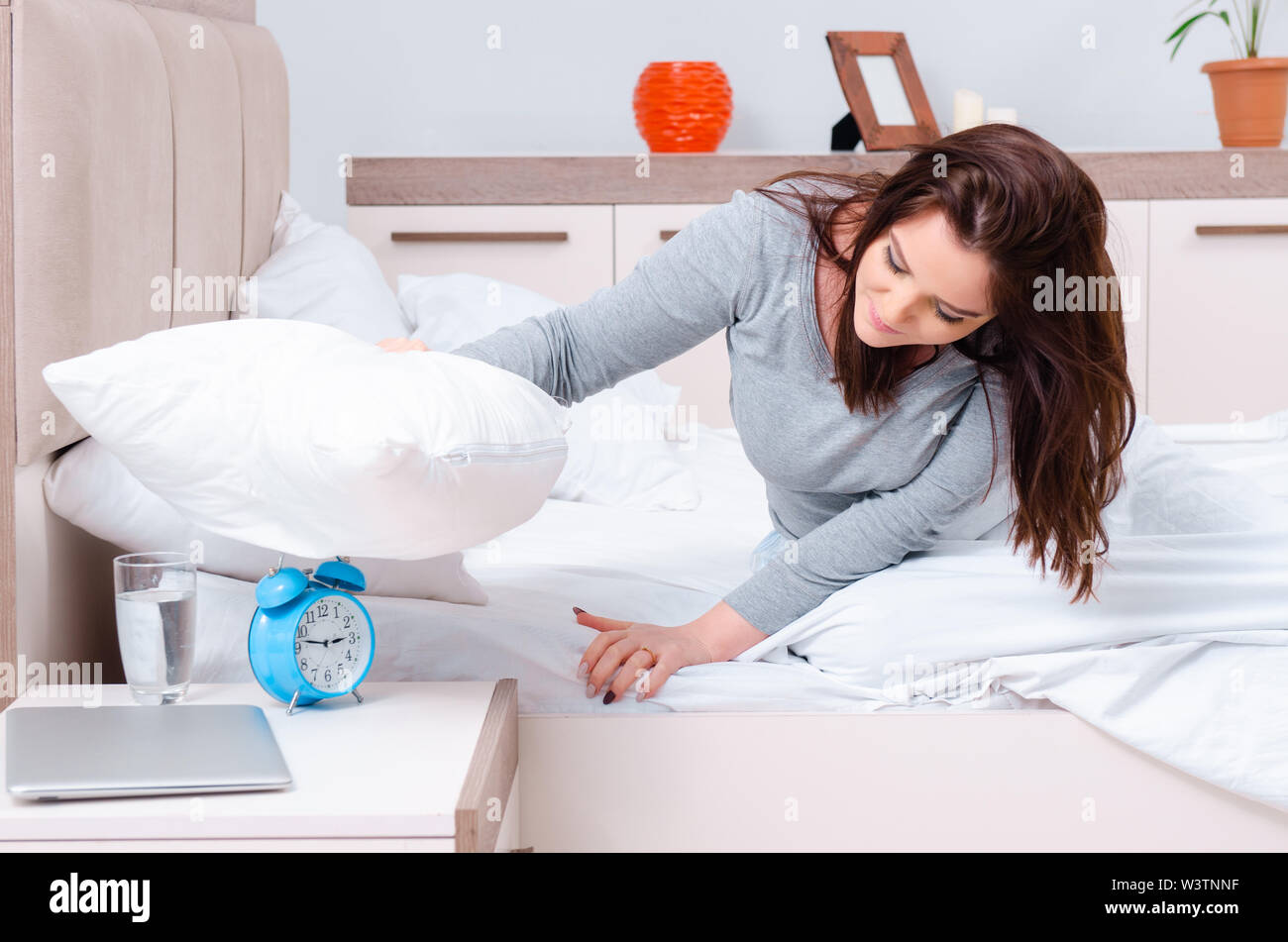 The young woman lying on the bed in time management concept Stock Photo
