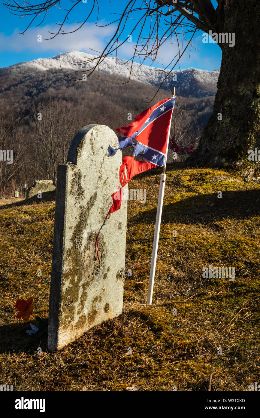 Tattered Confederate flag  beside a gravestone in a hilltop cemetery near Bakersville, Mitchell County, North Carolina, USA. Mitchell County is a coun Stock Photo