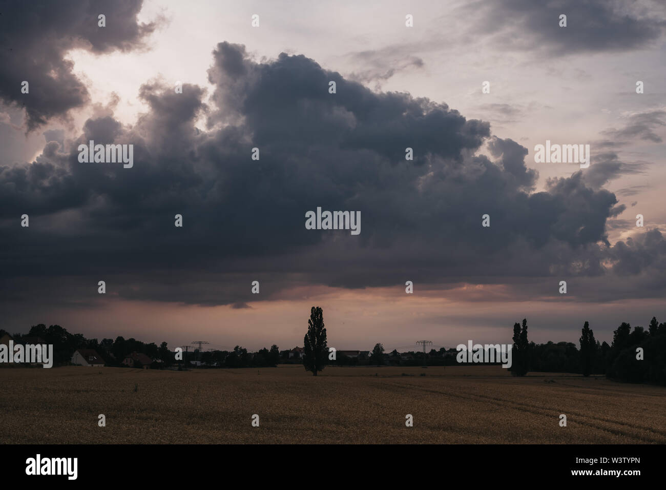 dramatic evening sky during sunset over field Stock Photo