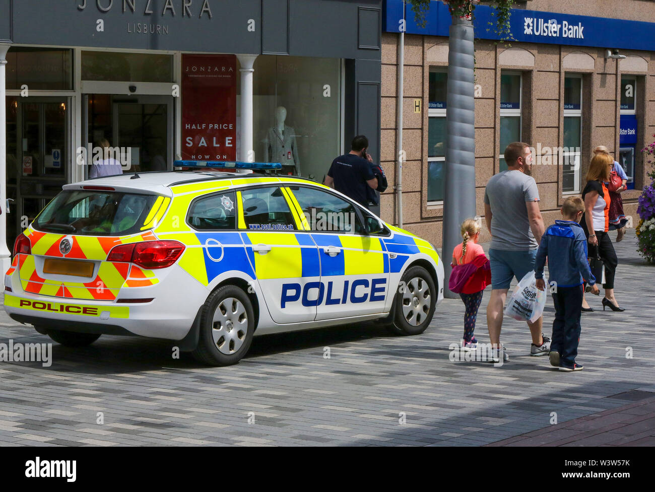 PSNI parked police car outside shop in a pedestrian zone with people walking past on a sunny afternoon in Lisburn, Northern Ireland. Editorial use onl Stock Photo