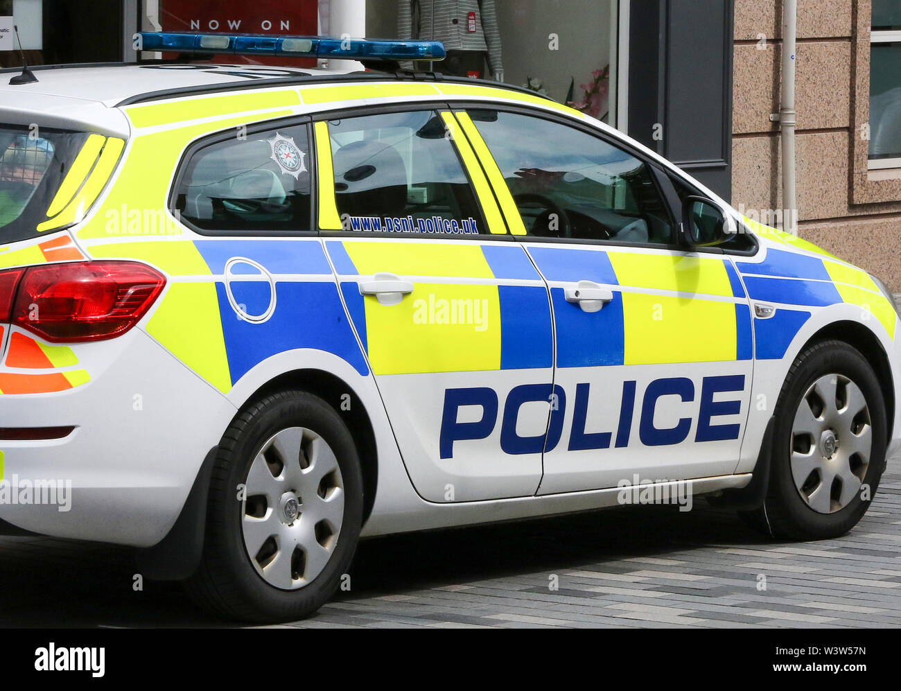 Side-view of a UK police car, a PSNI police car with PSNI logo and web address on side window, parked outside shop in pedestrian zone in Lisburn. Stock Photo