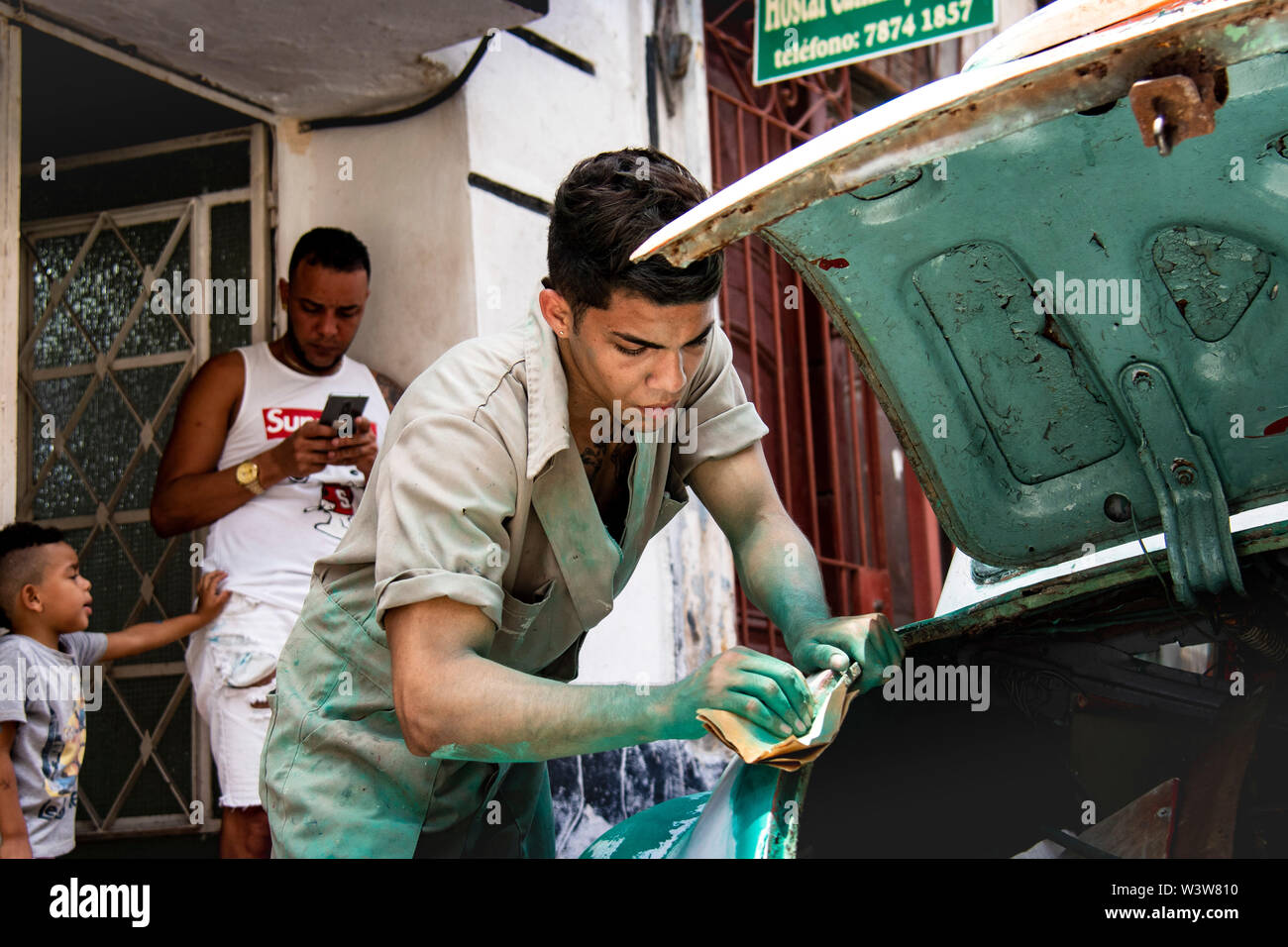 Cuban mechanic working on fixing up his classic car Stock Photo