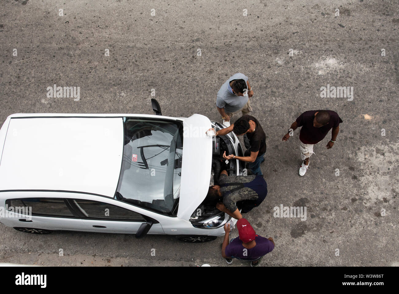 A group of men work on a car with the hood up on the street in Havana, Cuba Stock Photo