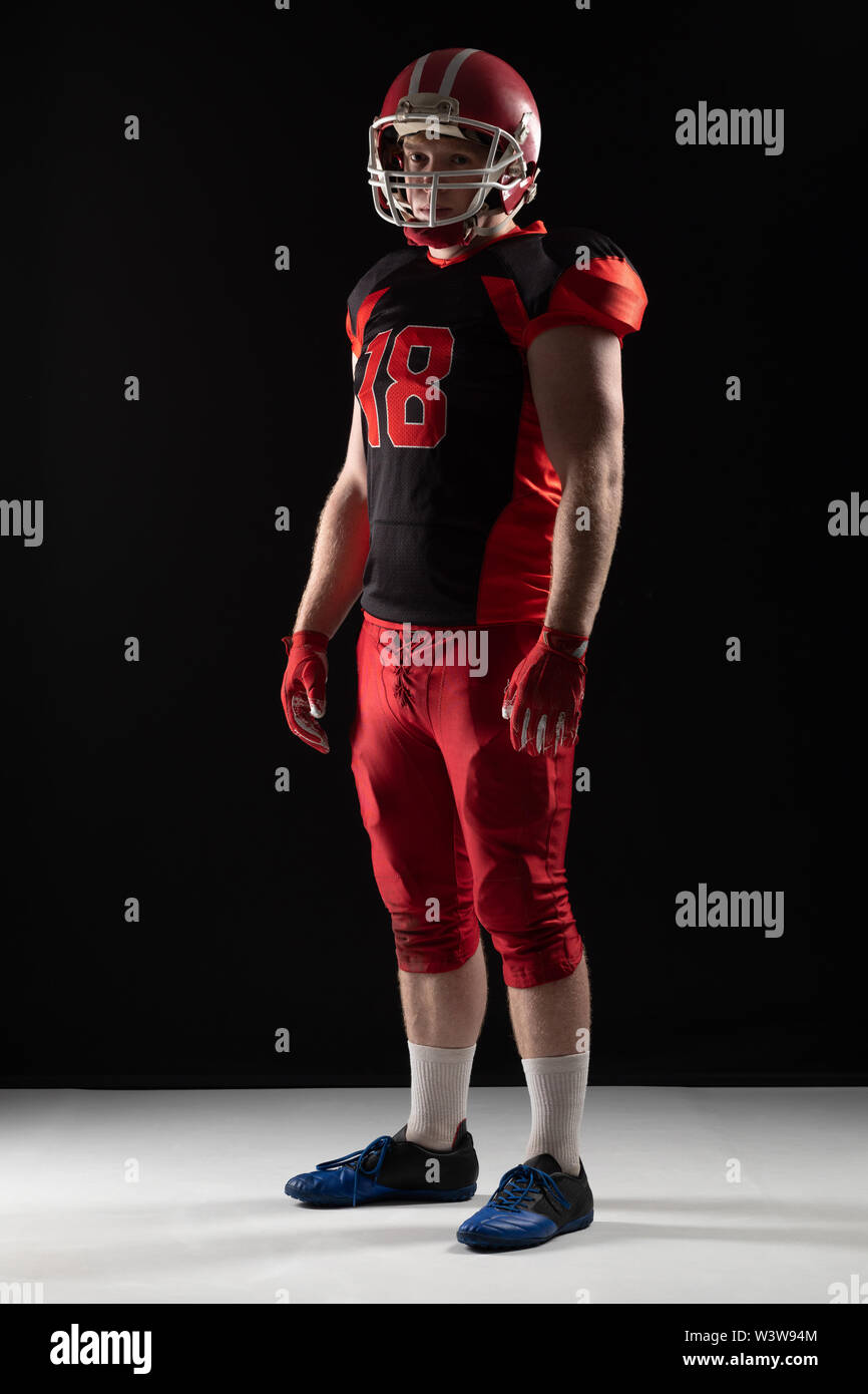 American football player in helmet standing against black background