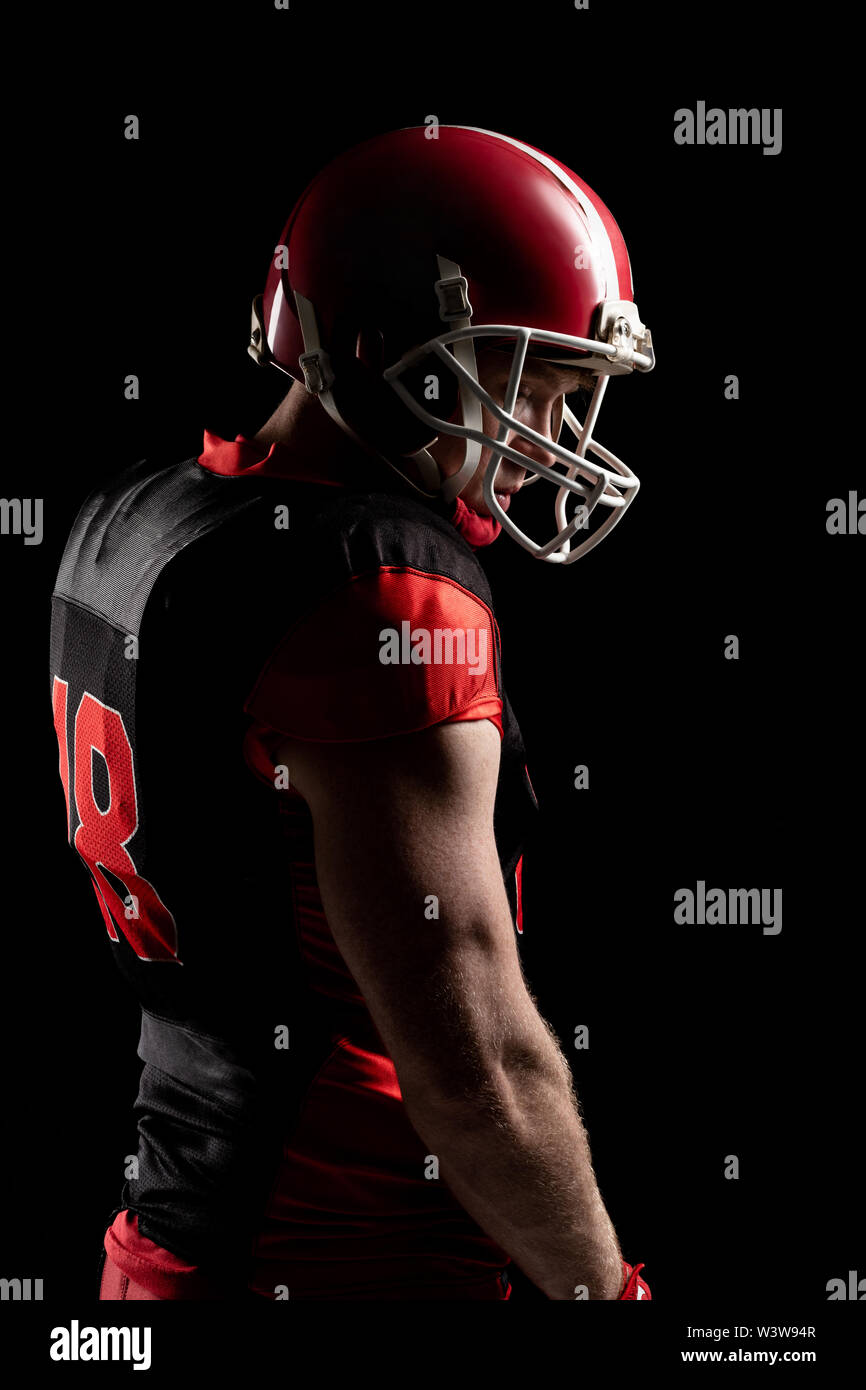 American football player in helmet standing against black background
