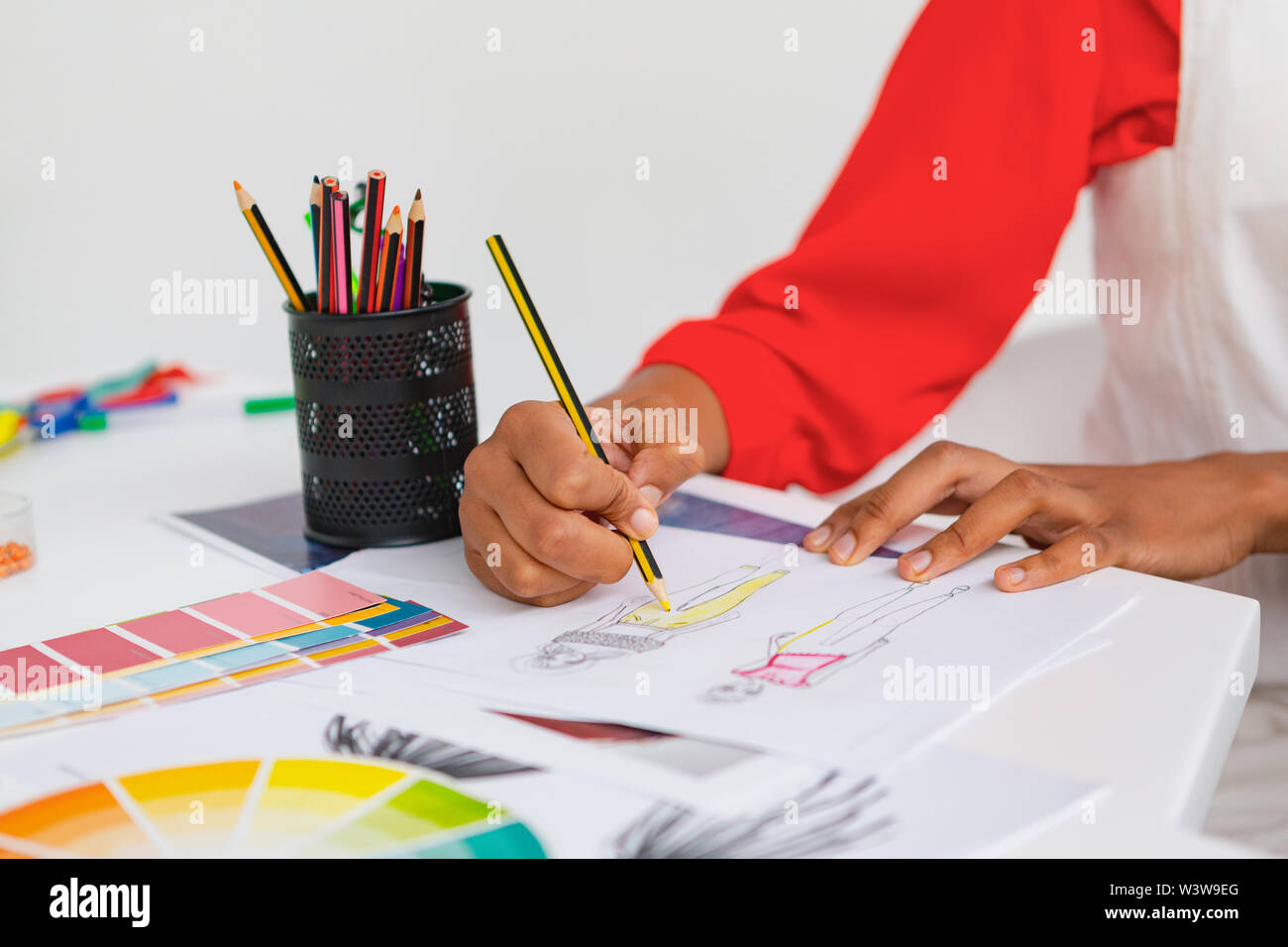 Female fashion designer drawing a sketch at desk in design studio Stock ...