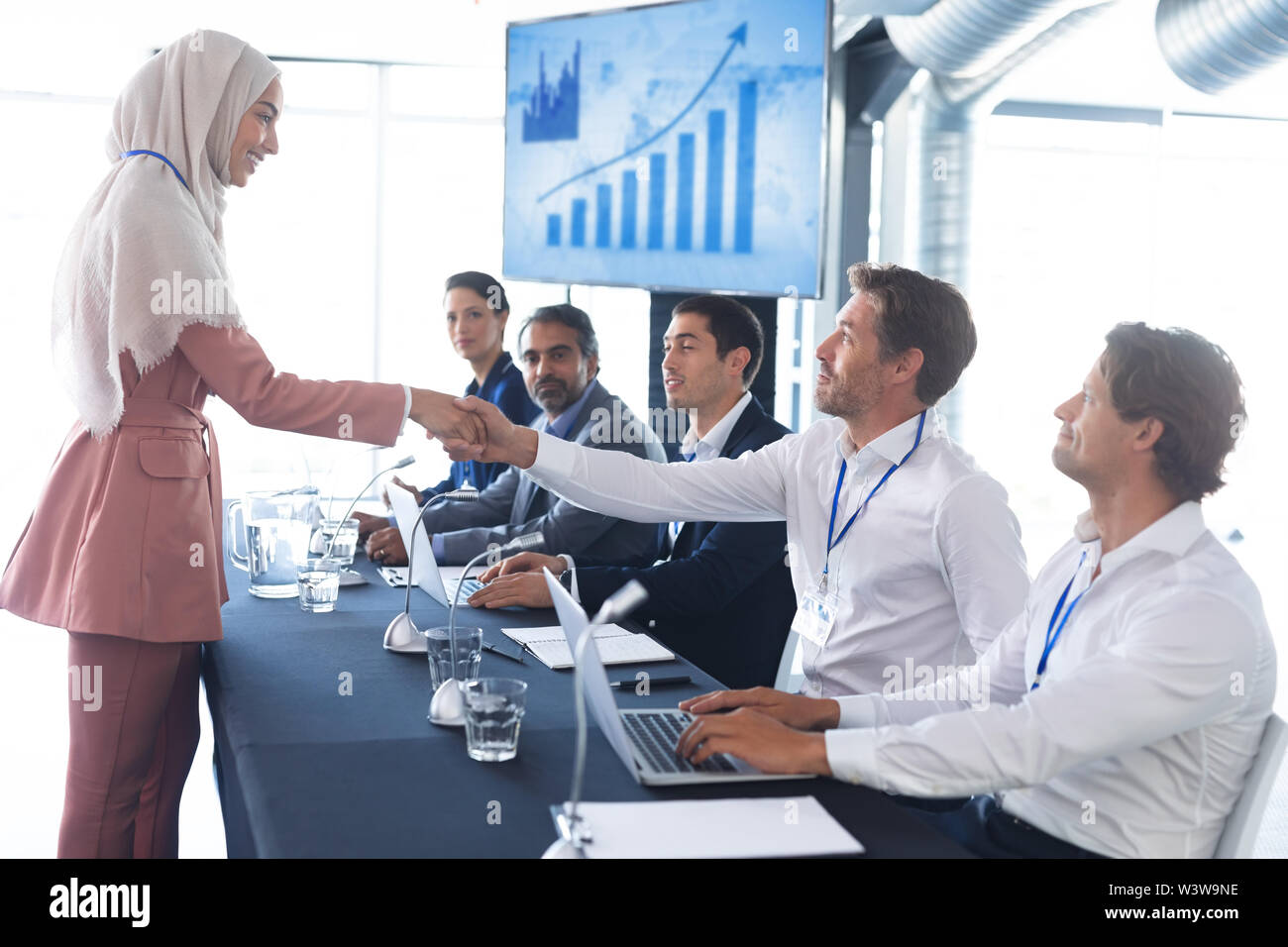 Business people shaking hands with each other while checking in business seminar Stock Photo