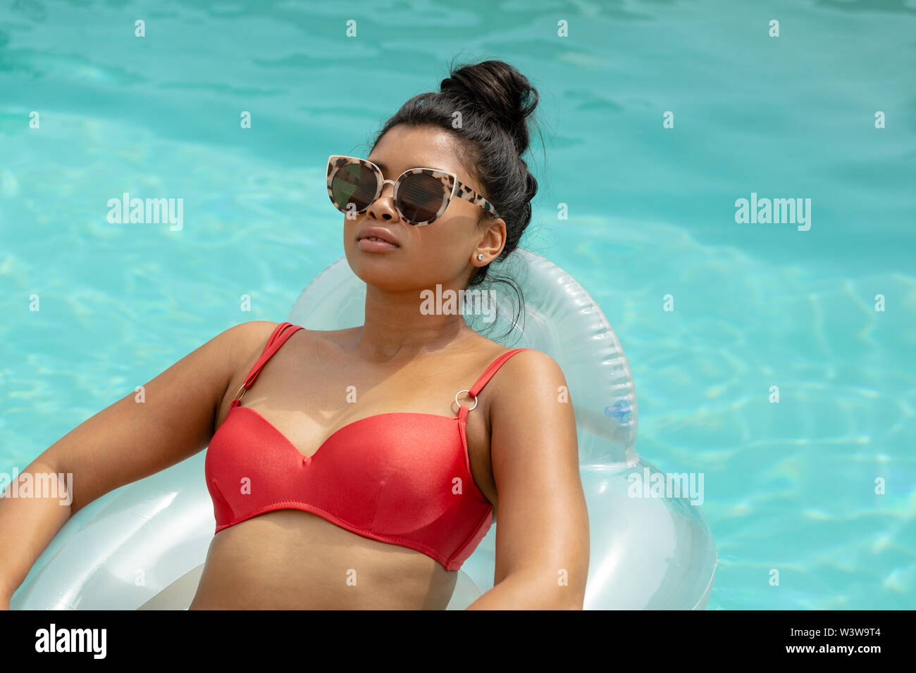 Woman in bikini relaxing on a inflatable tube in swimming pool at the  backyard of home Stock Photo - Alamy