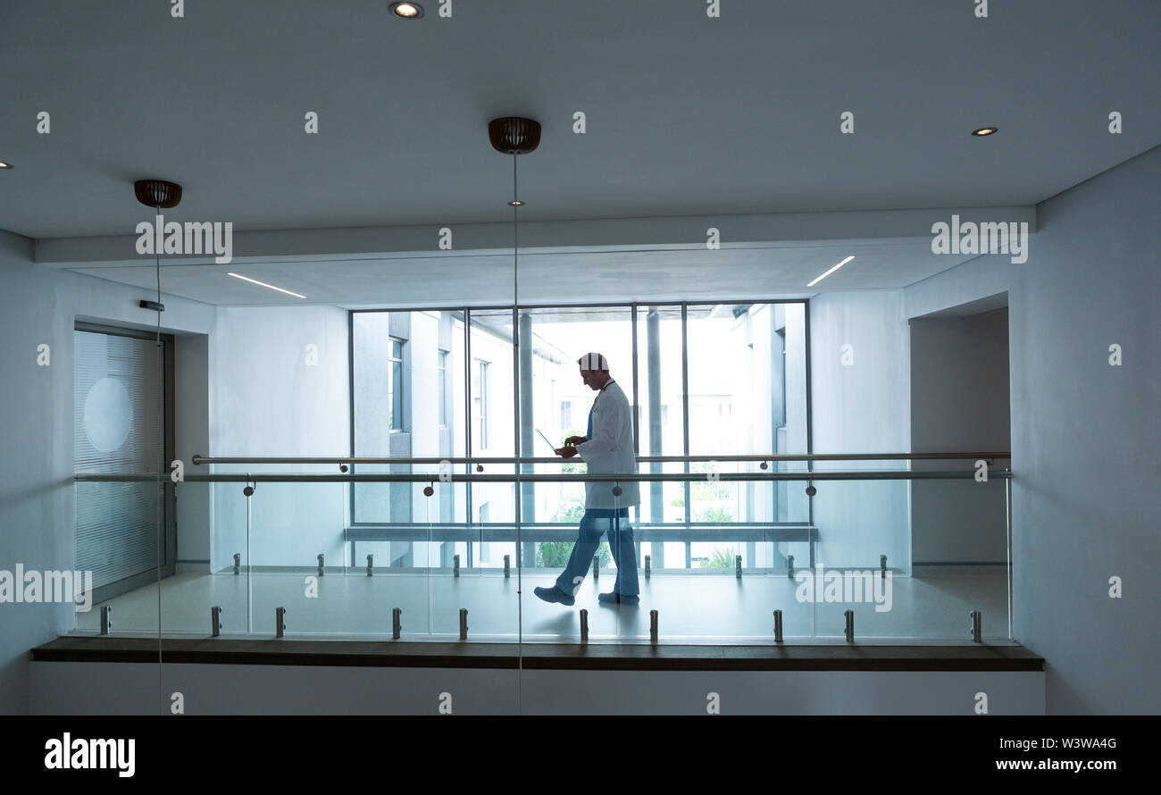 Male doctor using laptop while walking in the corridor Stock Photo