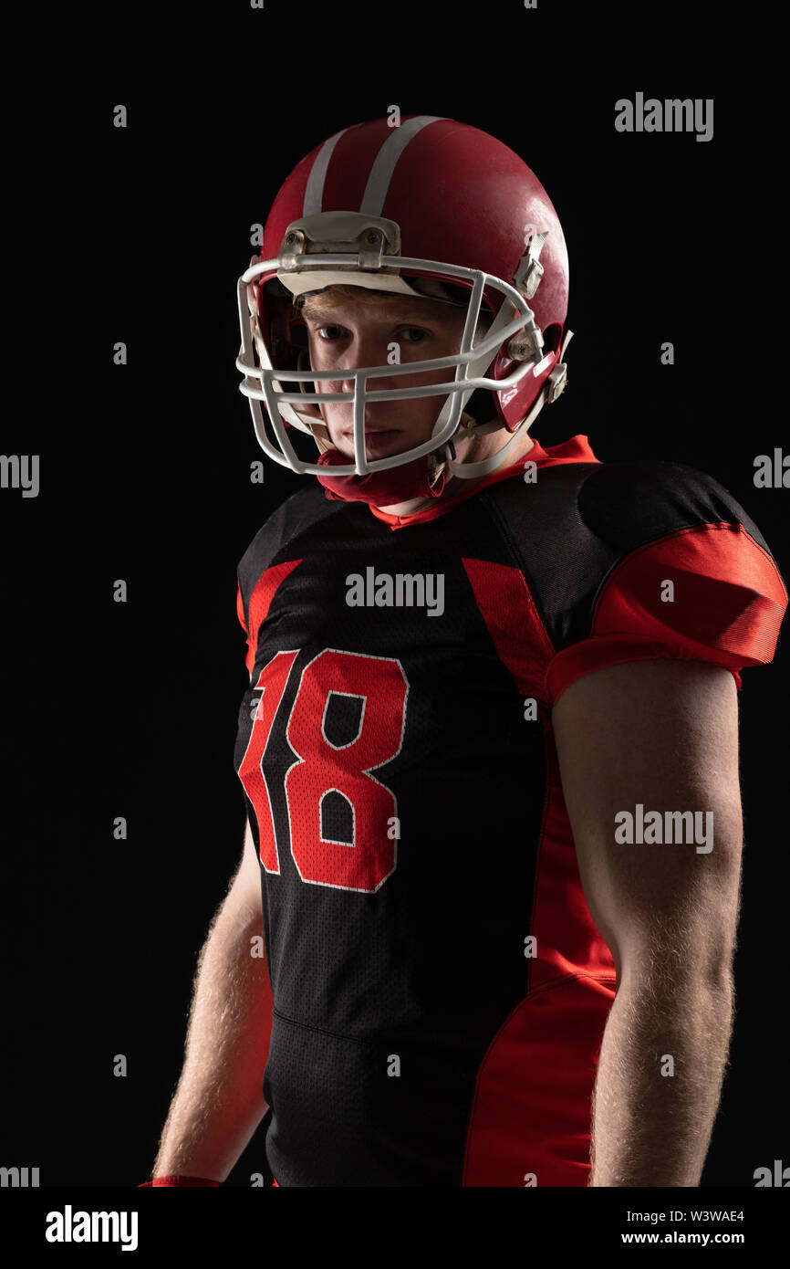 American football player in helmet standing against black background
