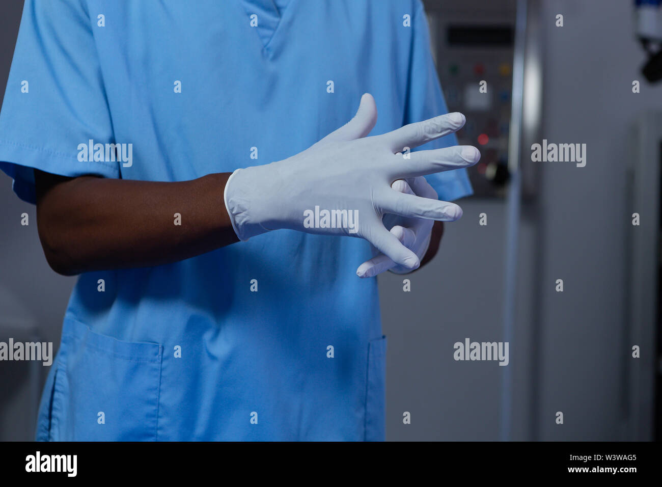 Male surgeon wearing surgical gloves in operating room of hospital