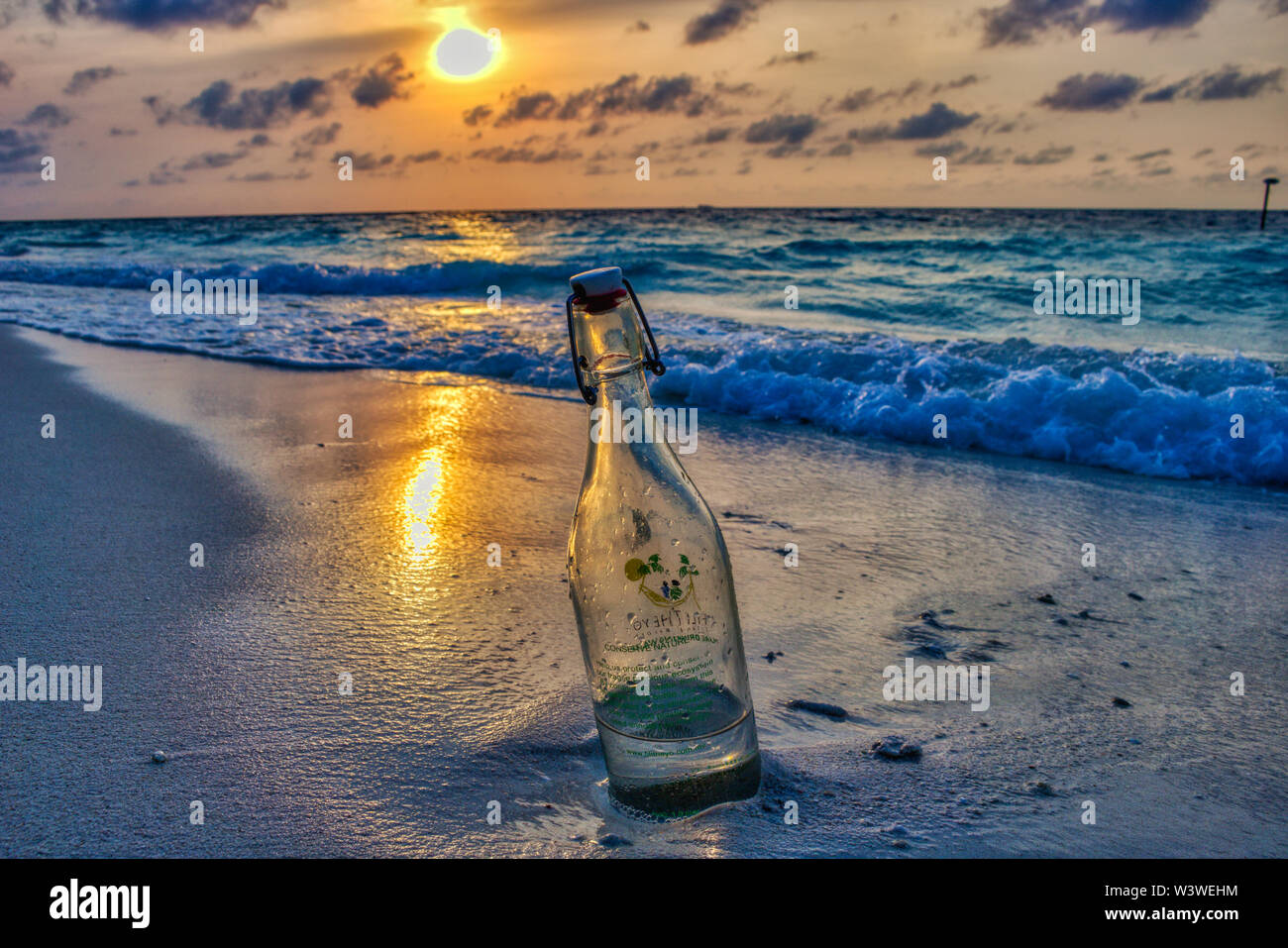 This unique photo shows a glass bottle of sand lying in your sun gear on the beach of the Maldives Stock Photo