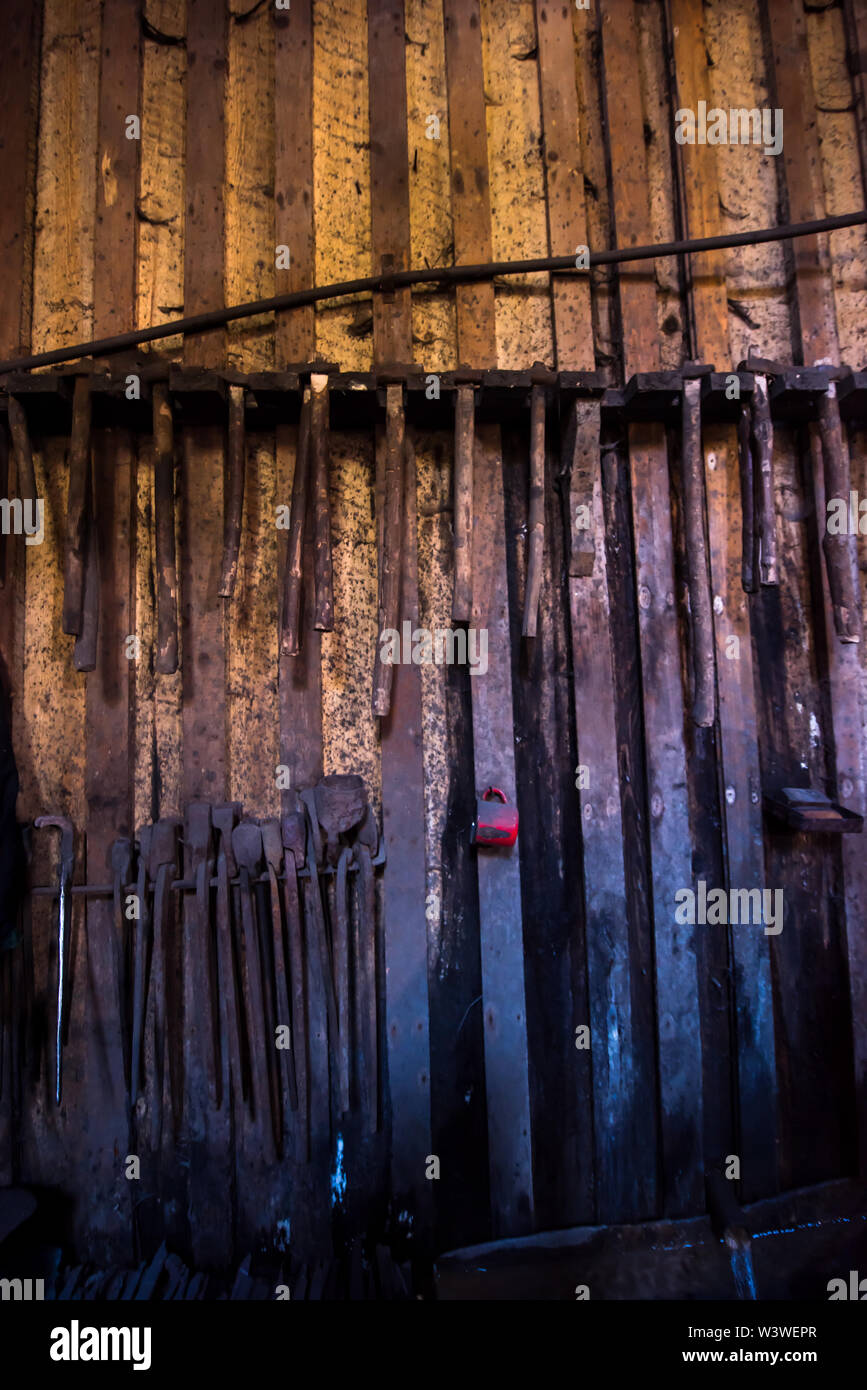 blacksmith tools hanging on a wooden wall Stock Photo