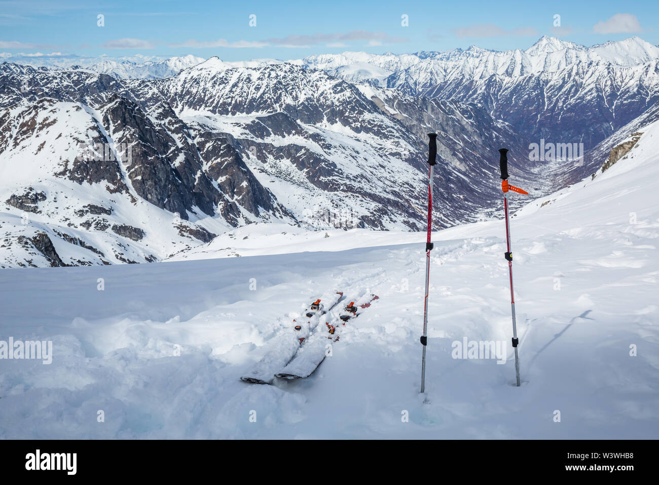 After a long hike, skis and poles sit near the top, overlooking a vast glacial valley below Snowbird Glacier in the Hatcher Pass area of the Talkeetna Stock Photo