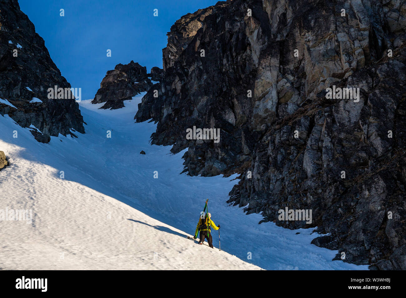 Backcountry skiing in Alaska, a skier hikes up a steep chute or couloir