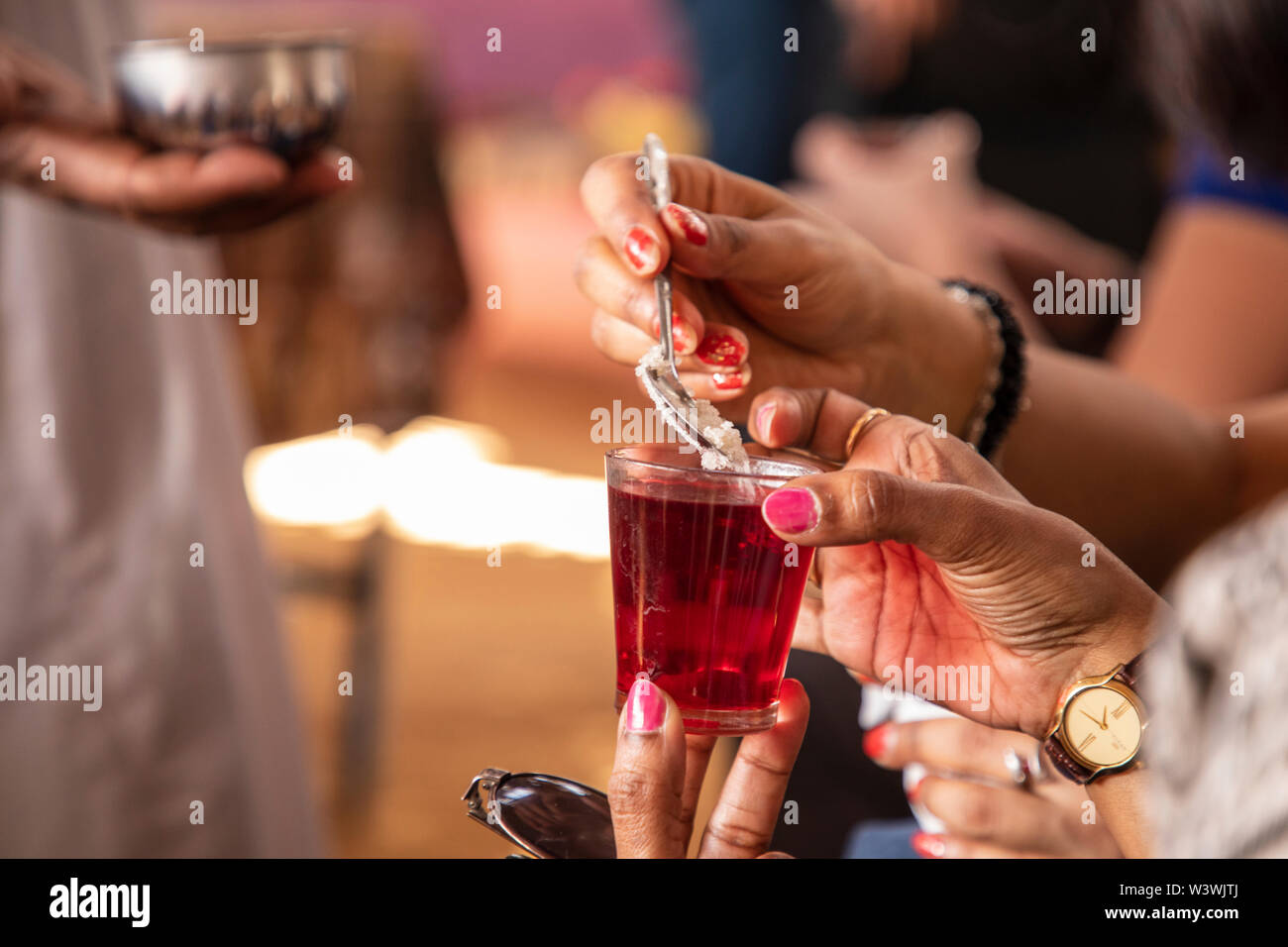 Adding a spoonful of sugar to a glass of hibiscus tea in Egypt Stock Photo