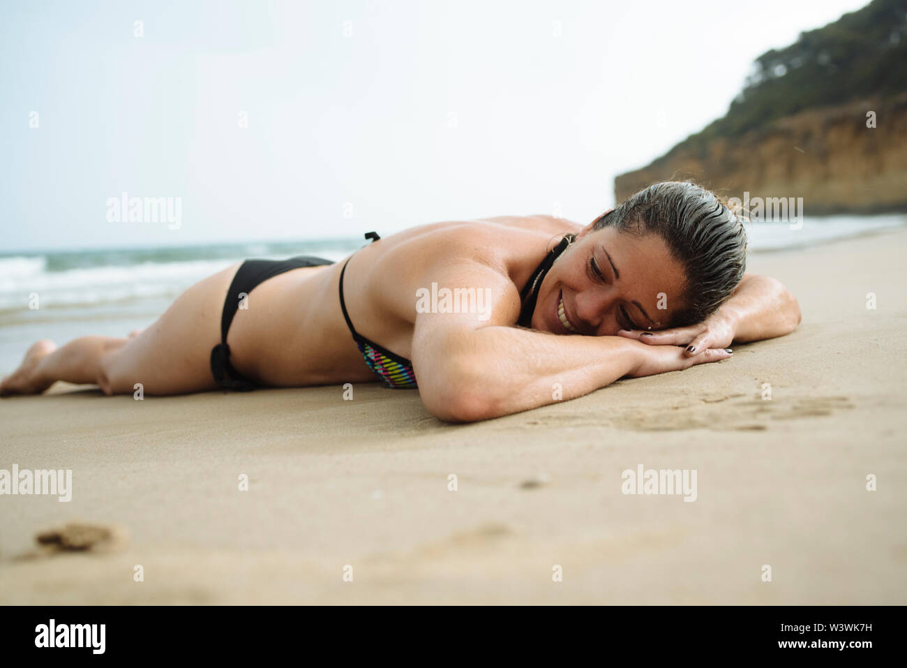 Pretty woman sunbathing and smiling on the beach sand. Stock Photo