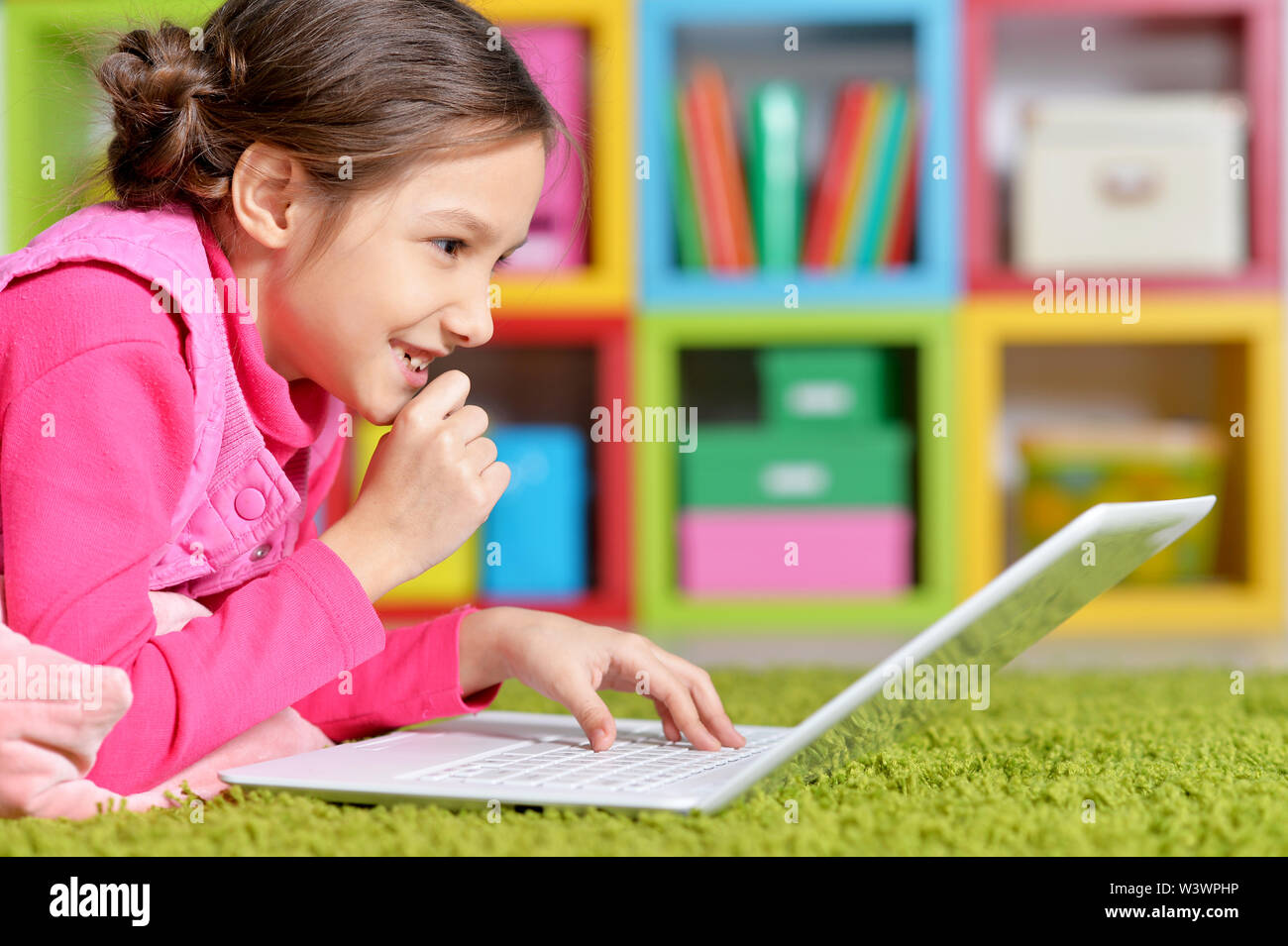 Emotional cute girl using laptop while lying on floor Stock Photo - Alamy