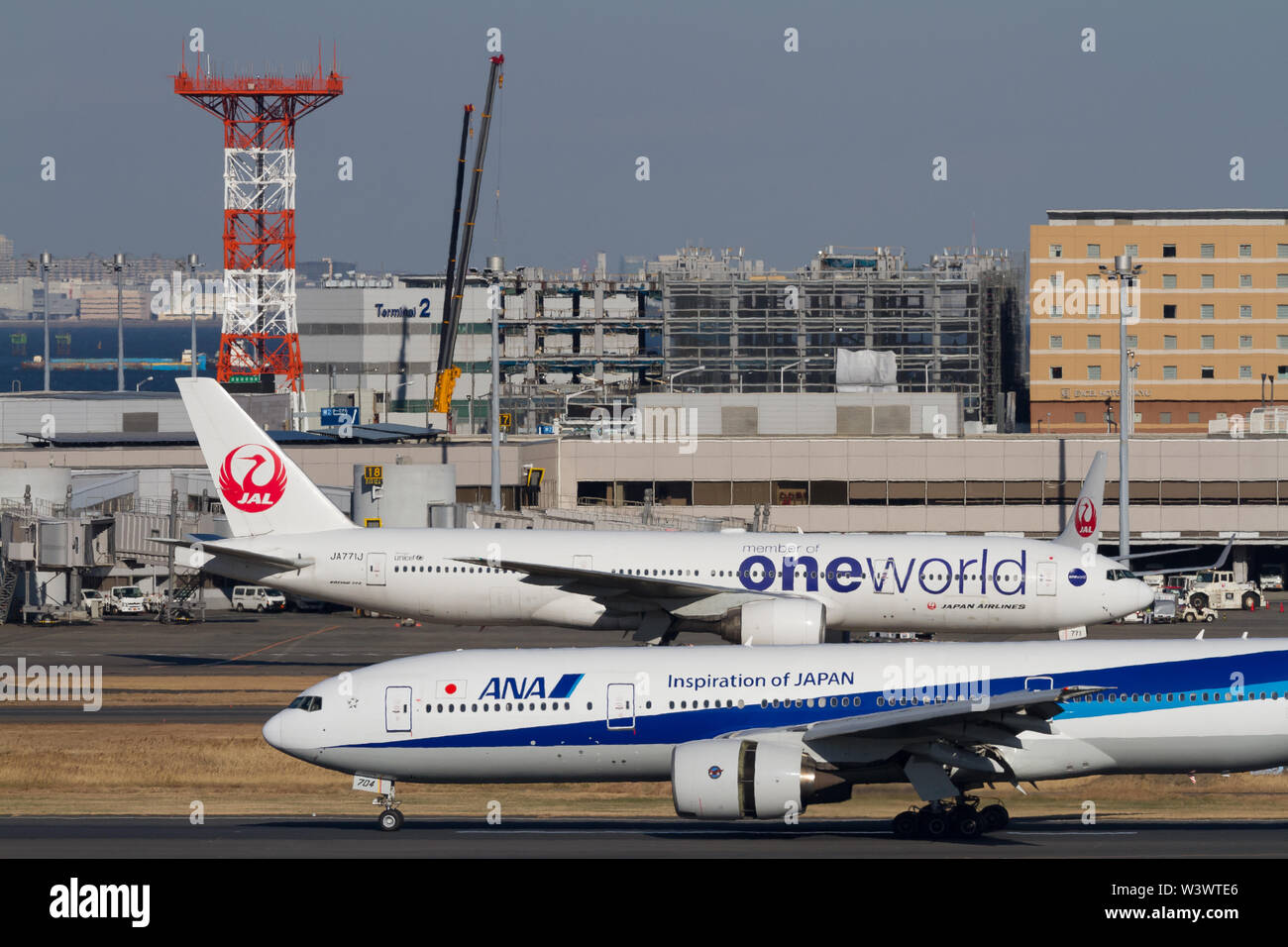 An All Nippon Airways (ANA)  Boeing 777-281 passes a Japan Airlines (JAL) Boeing 777-246 at Haneda International Airport, Tokyo, Japan. Stock Photo