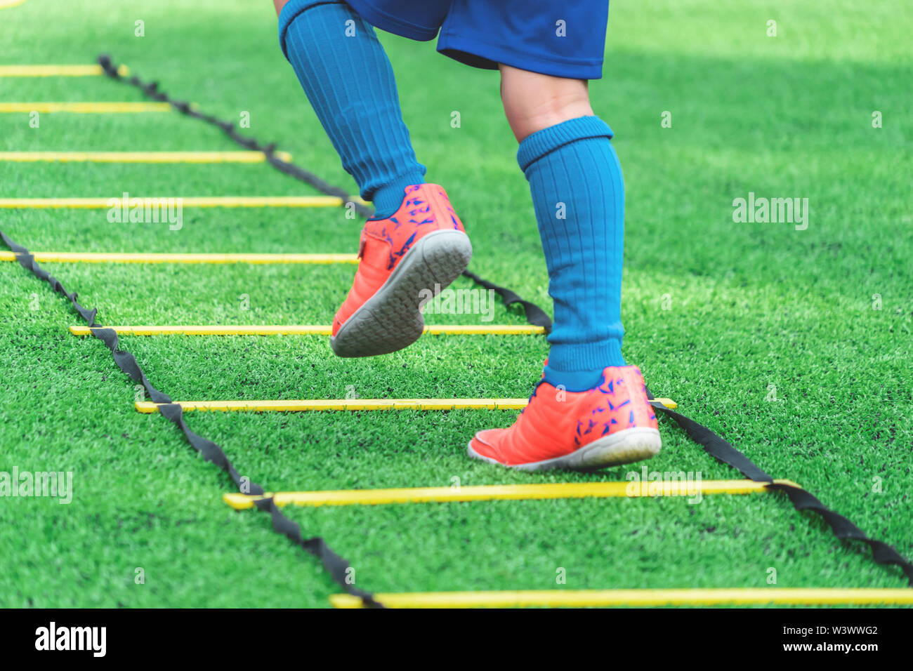 Child feet with soccer boots training on agility speed ladder in soccer training. Stock Photo