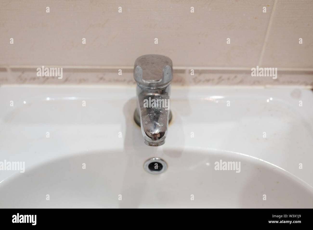 Dirty stainless bathroom tap.Bathroom tap and ceramic sink Stock Photo
