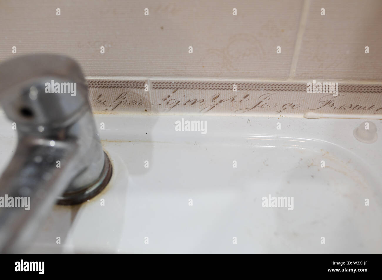 Dirty stainless bathroom tap.Bathroom tap and ceramic sink Stock Photo