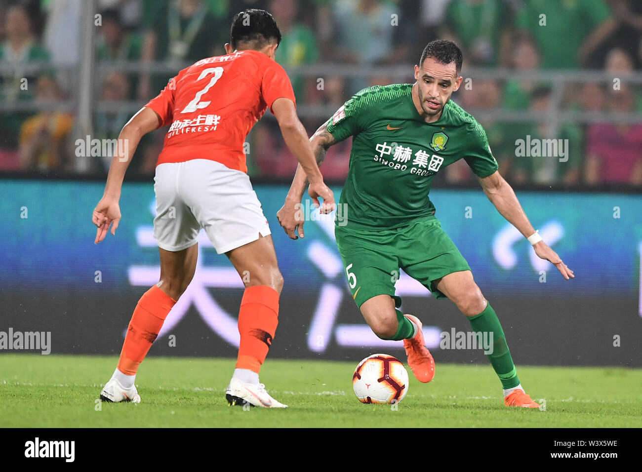 Brazilian football player Renato Soares de Oliveira Augusto, or simply Renato Augusto, right, of Beijing Sinobo Guoan passes the ball against a player of Beijing Renhe in their 18th round match during the 2019 Chinese Football Association Super League (CSL) in Beijing, China, 17 July 2019. Beijing Sinobo Guoan defeated Beijing Renhe 2-1. Stock Photo