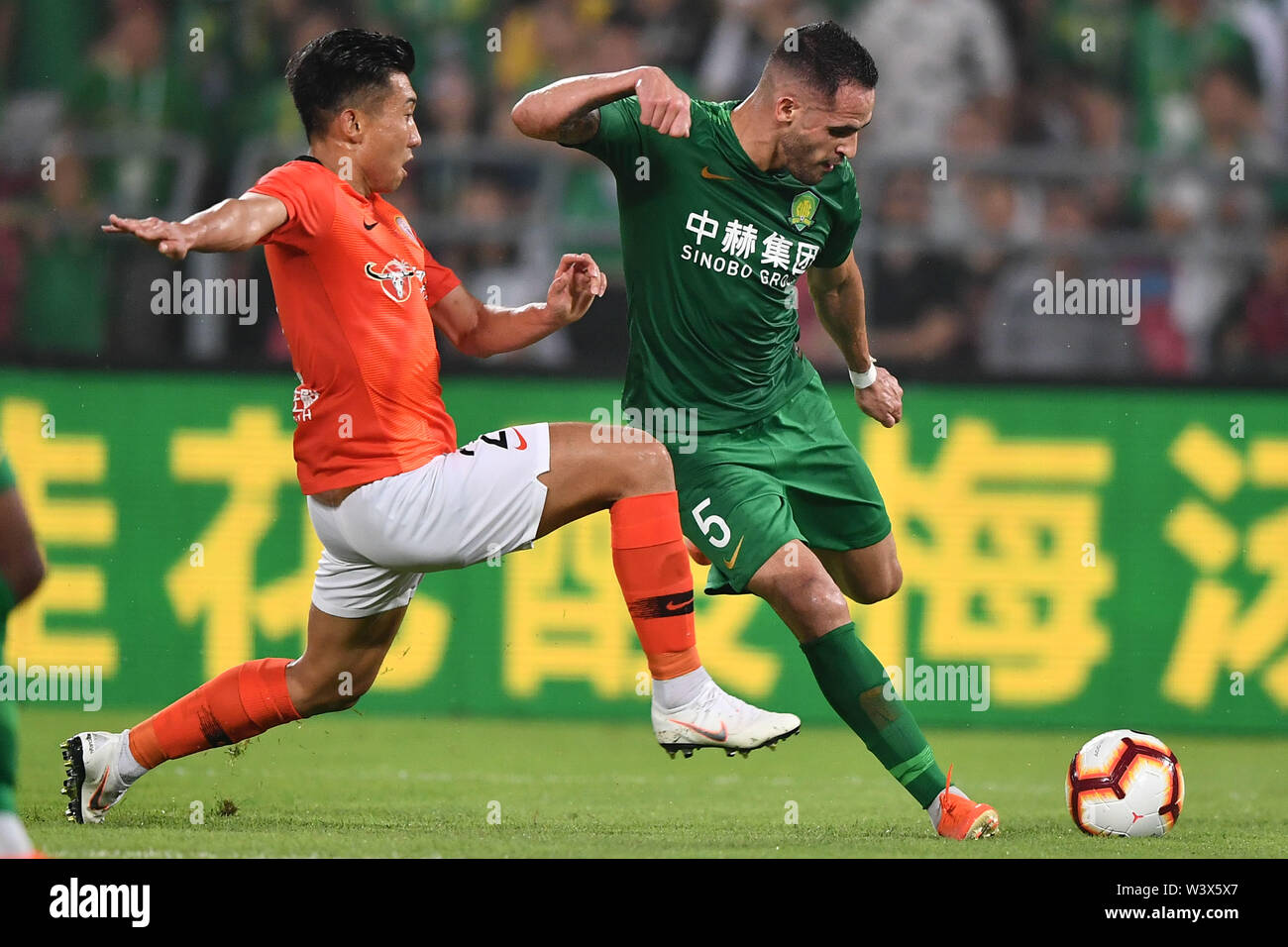 Brazilian football player Renato Soares de Oliveira Augusto, or simply Renato Augusto, right, of Beijing Sinobo Guoan passes the ball against a player of Beijing Renhe in their 18th round match during the 2019 Chinese Football Association Super League (CSL) in Beijing, China, 17 July 2019. Beijing Sinobo Guoan defeated Beijing Renhe 2-1. Stock Photo