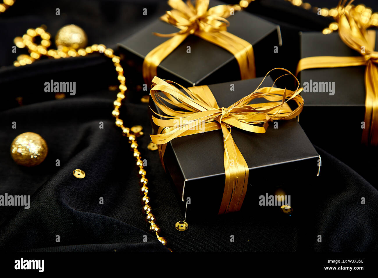 Luxury black gift boxes with gold ribbon on shine background. Christmas ...