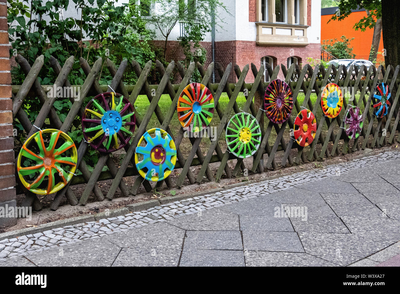 Unusual garden fence . Trellis-style wood logs & painted hubcaps . Karwendel strasse, Berlin-Lichterfelde Stock Photo