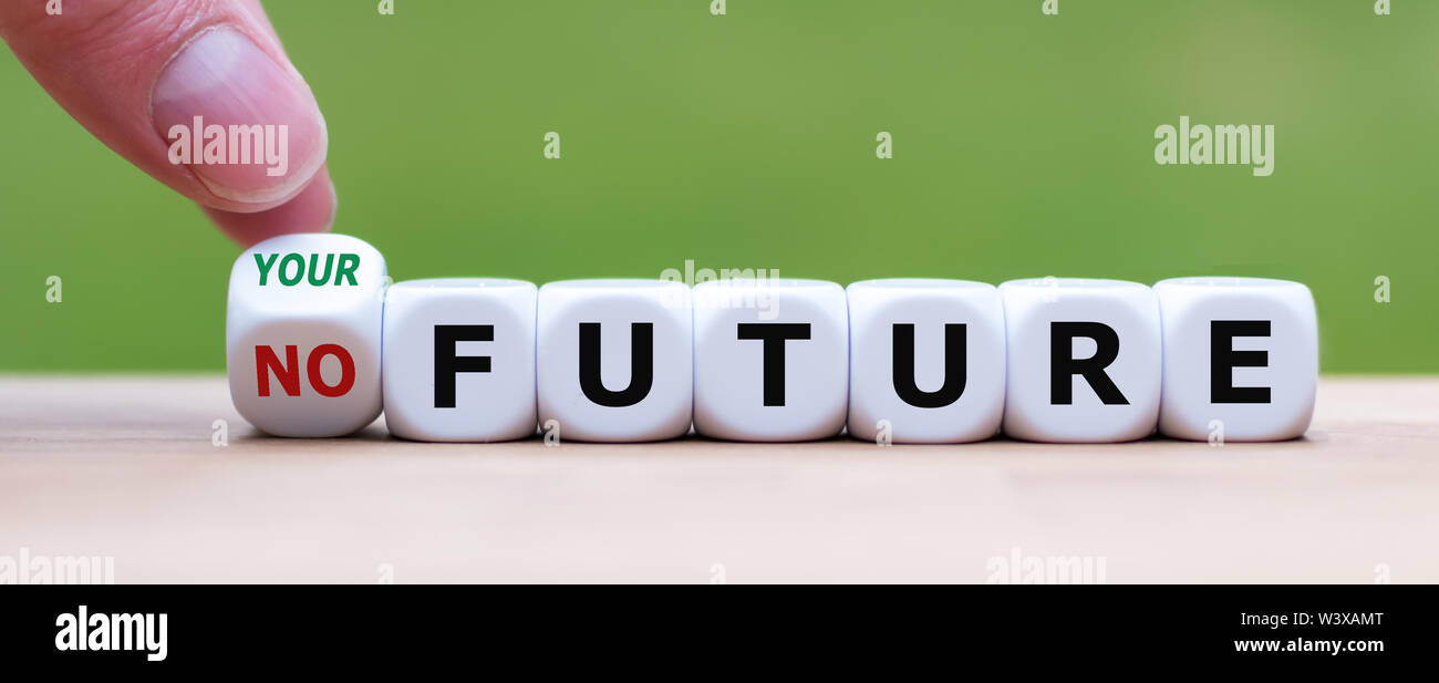 Hand turns a dice and changes the expression 'no future' to 'your future'. Stock Photo
