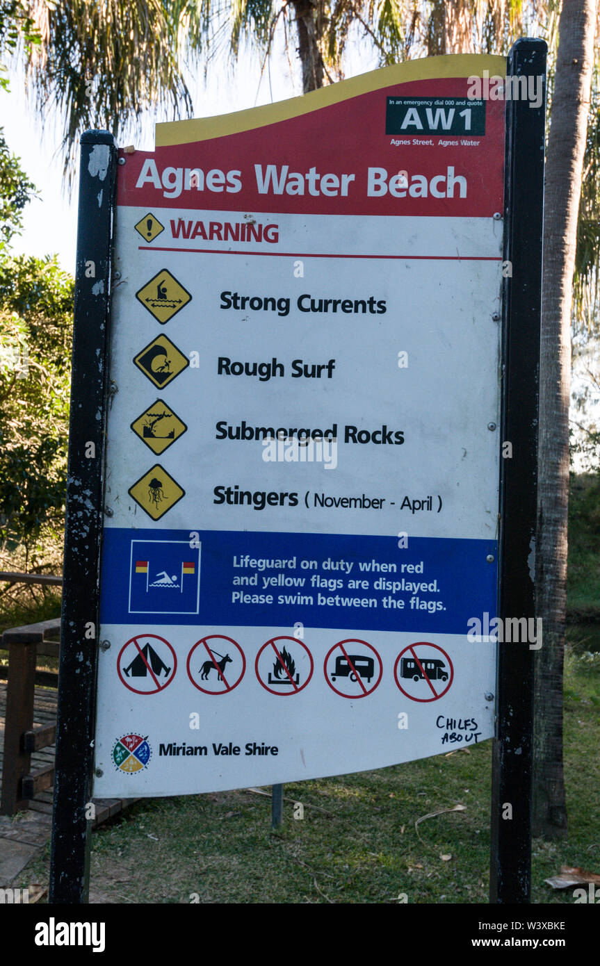 A beach swimmers warning sign on the long and wide sandy coastline at Agnes Water, a small town and popular holiday resort on the tropical coast of Qu Stock Photo