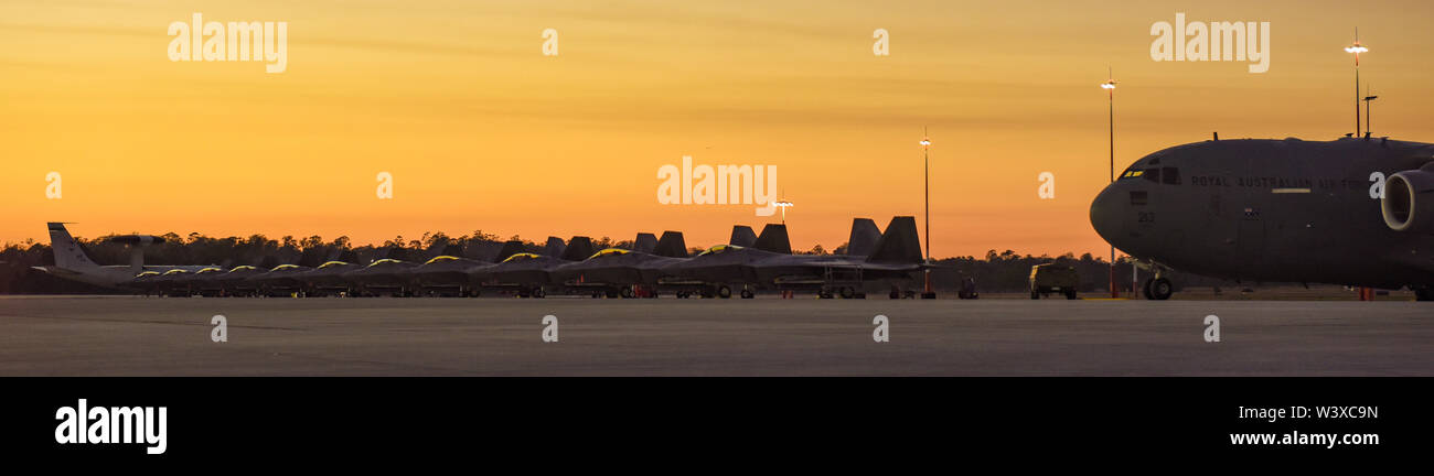 11 USAF F-22 Raptors and one airborne warning and control system (AWACS) E-3 Sentry are parked next to a Royal Australian Air Force C-17 Globemaster III on the RAAF Base Amberley flightline, July 17. The aircraft are participating in Exercise Talisman Sabre 19, a bilateral exercise that provides realistic, relevant training necessary to maintain and strengthen regional security, peace and stability. (U.S. Air Force photo by Staff Sgt. Kyle Johnson) Stock Photo