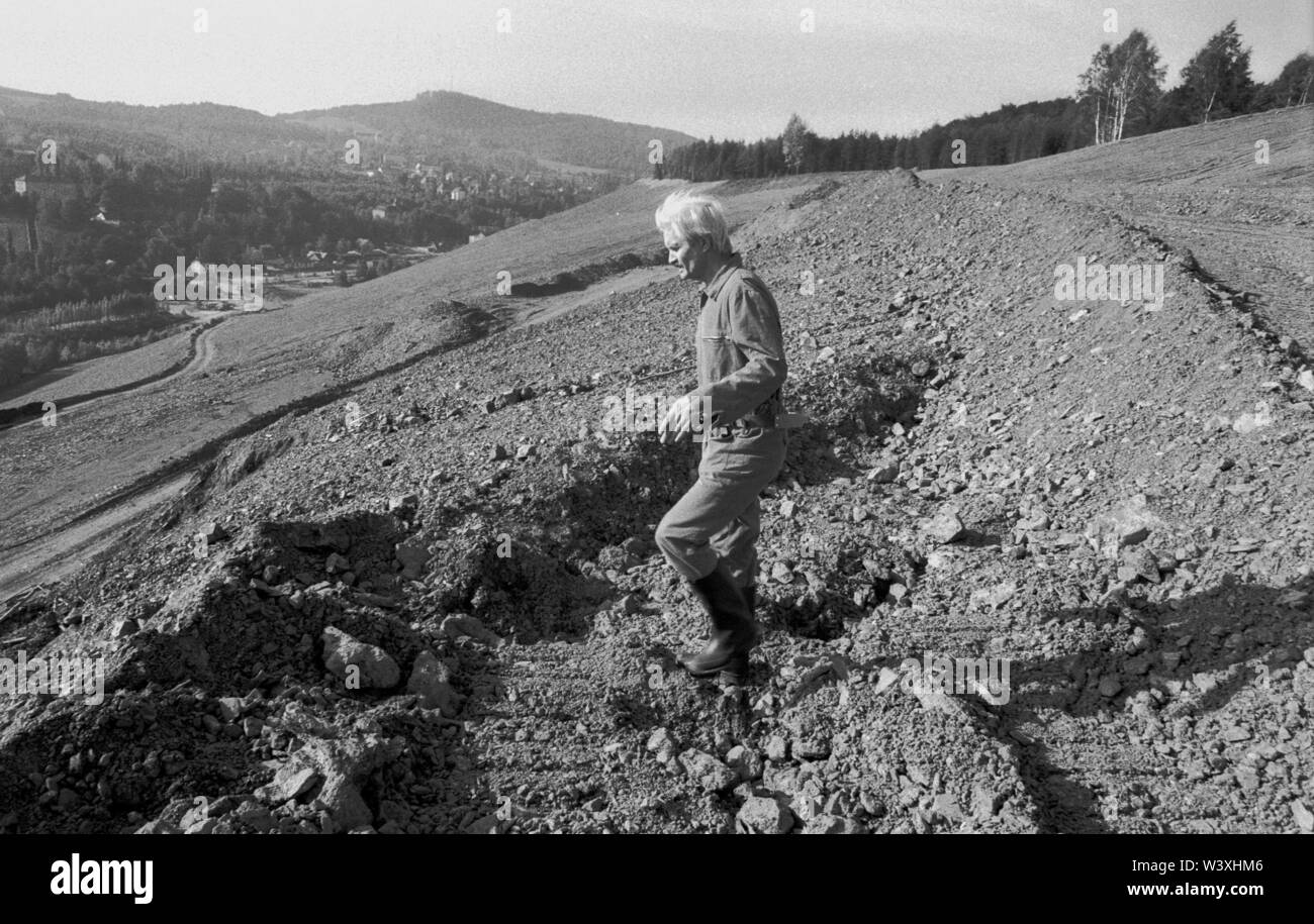 FILED - 01 January 1992, Berlin, Aue: Saxony/GDR/Energy/1992 Uranium dumps in Schlema near Aue, The remediation of major environmental damage has begun. The heap is flattened and terraces are laid out, bushes are planted. Access for the population will not be possible for a very long time. The renovation will be carried out by WISMUT AG. An excavator distributes a mixture of topsoil and ash // Erzgebirge/Environment/Atom/Uranium/Mining The German-Soviet joint stock company was founded after the emergence of the GDR to allow the Soviet Union further access to uranium in the Erzgeb Stock Photo