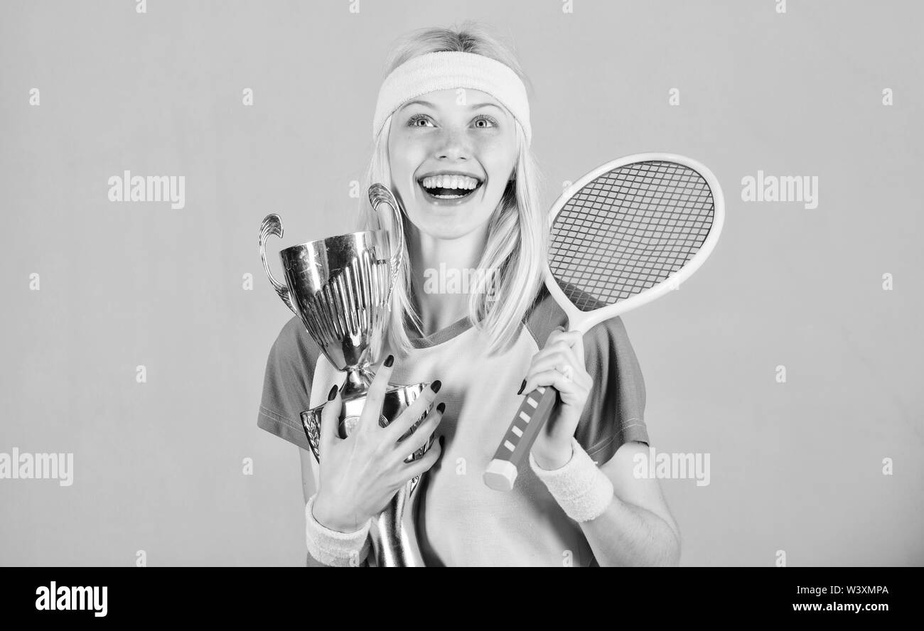 First place. Sport achievement. Celebrate victory. Tennis champion. Athletic girl hold tennis racket and golden goblet. Win tennis game. Tennis player win championship. Woman wear sport outfit. Stock Photo