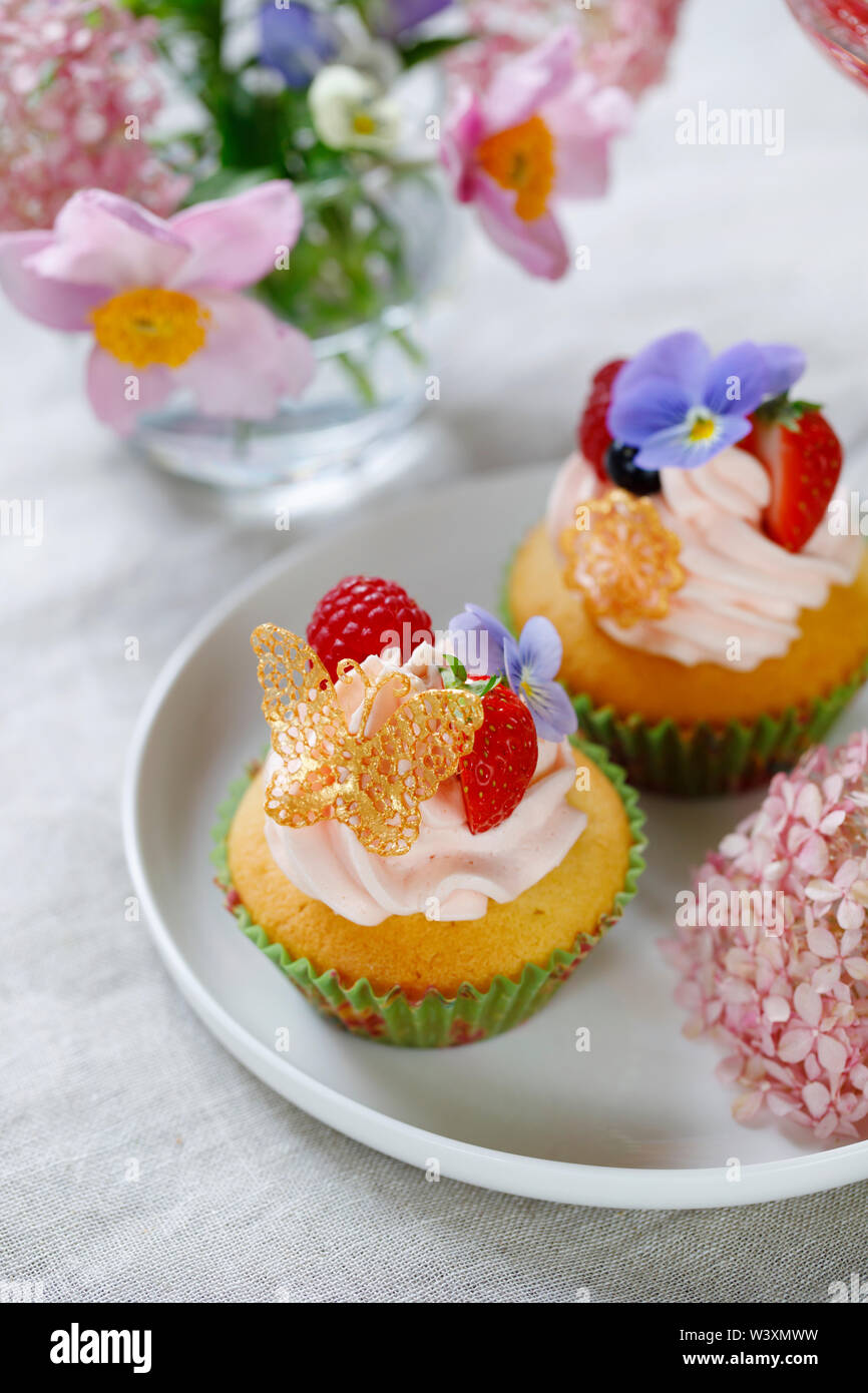 Cupcake decorated with buttercream, fruits and flowers Stock Photo