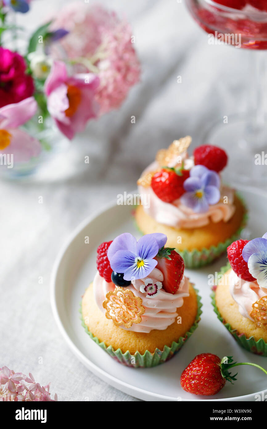 Cupcake decorated with buttercream, fruits and flowers Stock Photo