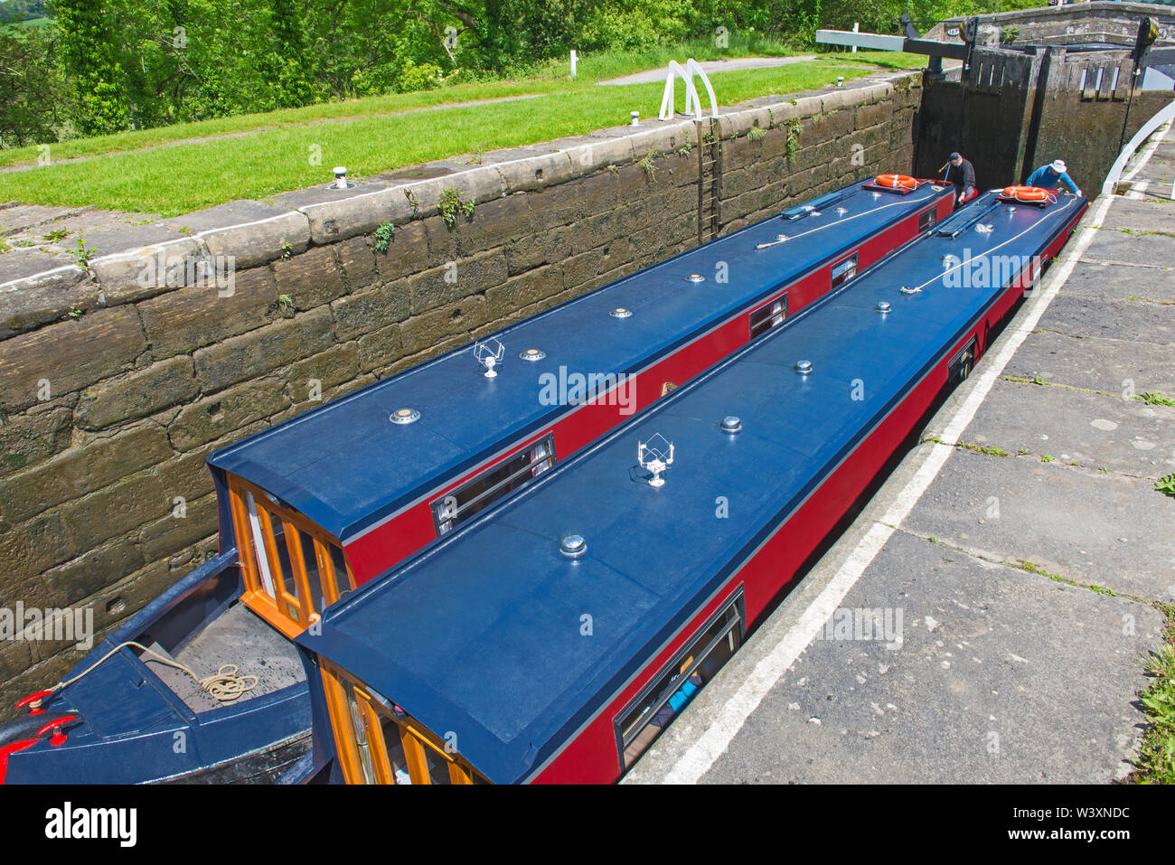 Two narrowboats traveling through a deep lock in English rural
