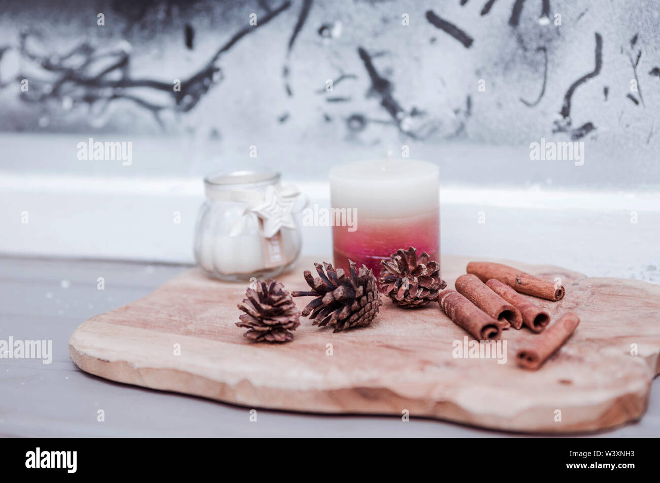 New Year's decor of fir cones, cinnamon sticks and candles on the windowsill Stock Photo