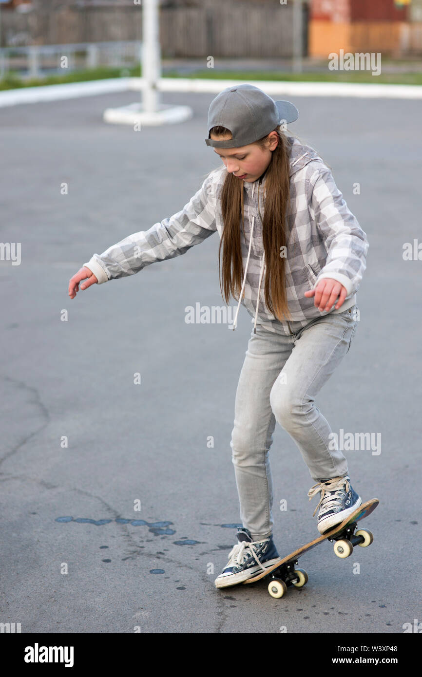 child girl outdoors studying skateboard tricks Stock Photo