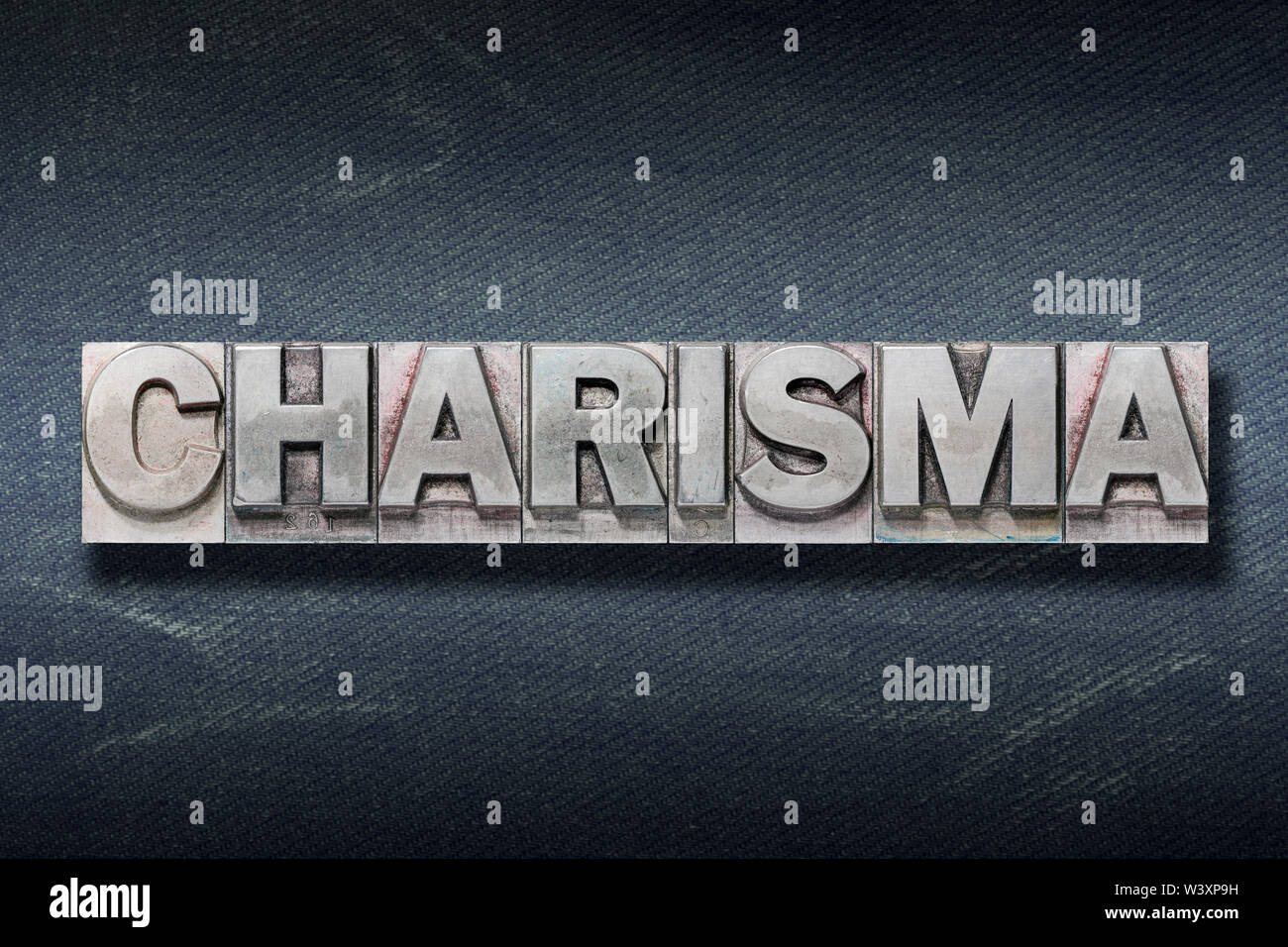 charisma word made from metallic letterpress on dark jeans background Stock Photo