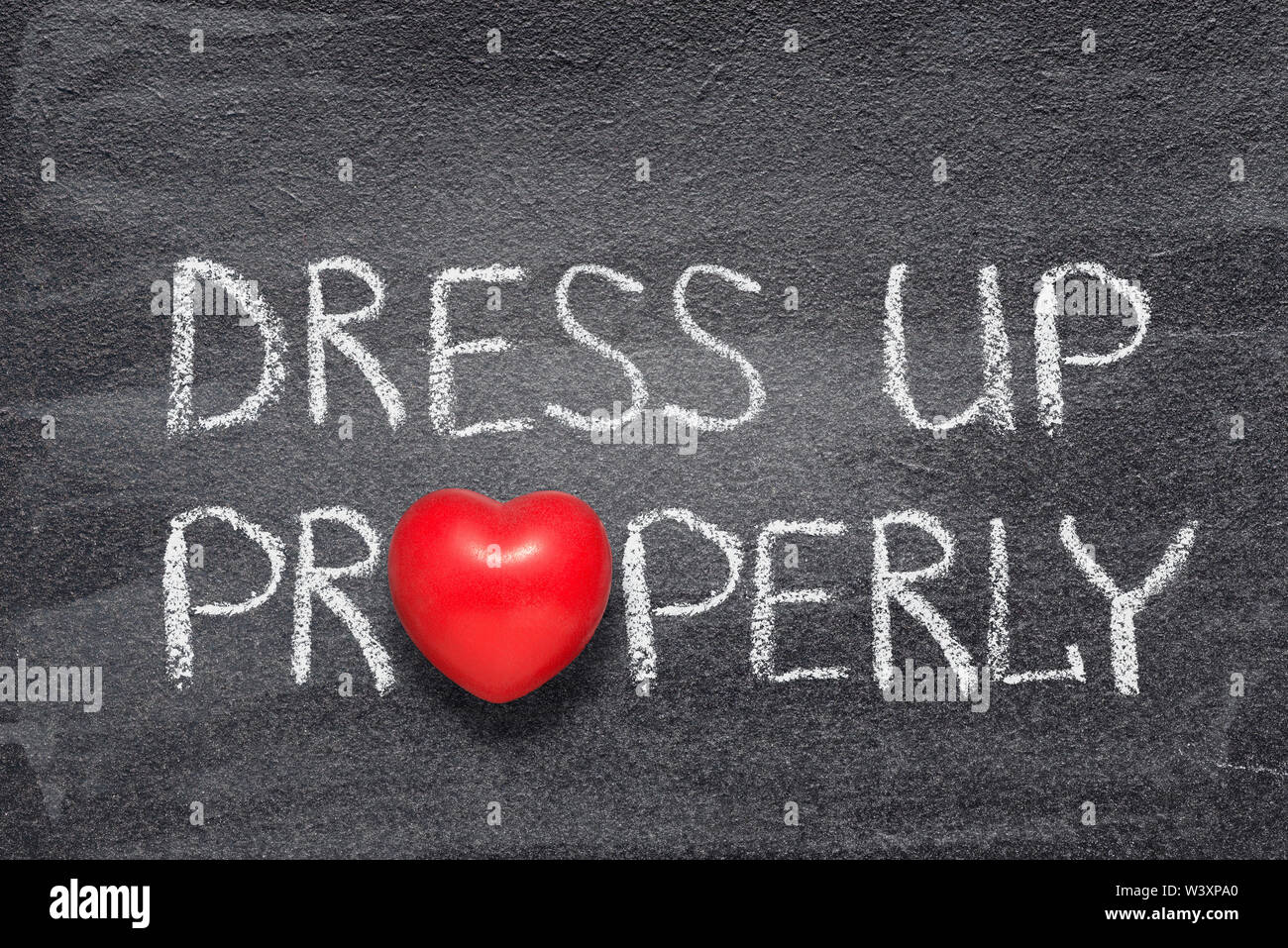 dress up properly phrase handwritten on chalkboard with red heart symbol instead of O Stock Photo