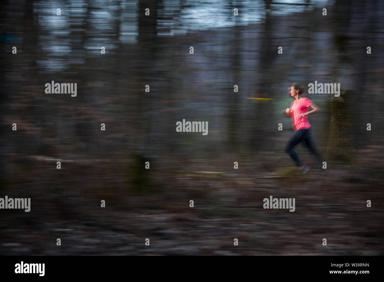 Young woman running outdoors in a forest, going fast (motion blurred ...